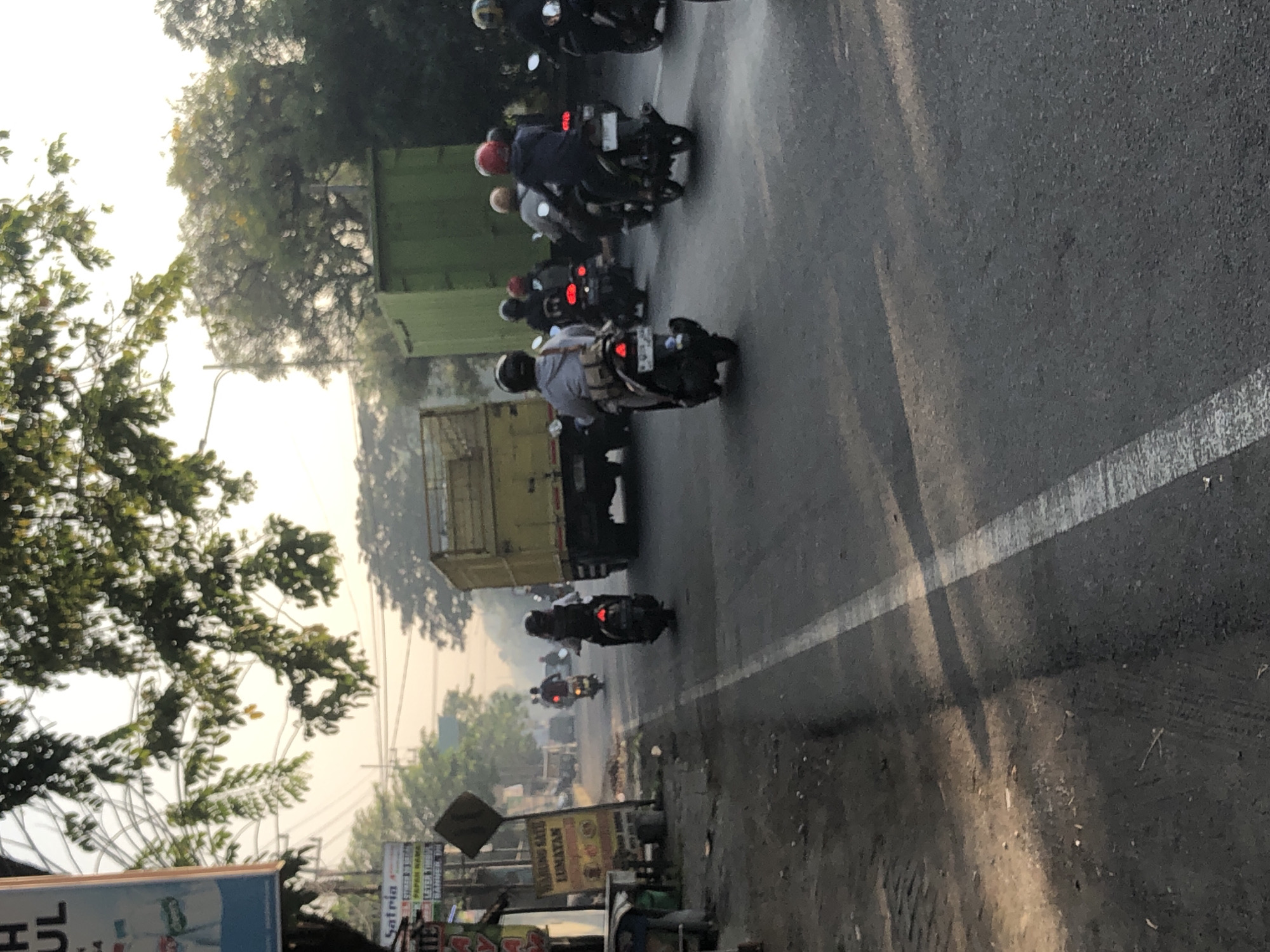 Heavy motorcycle traffic flows through Kludan on a hazy morning