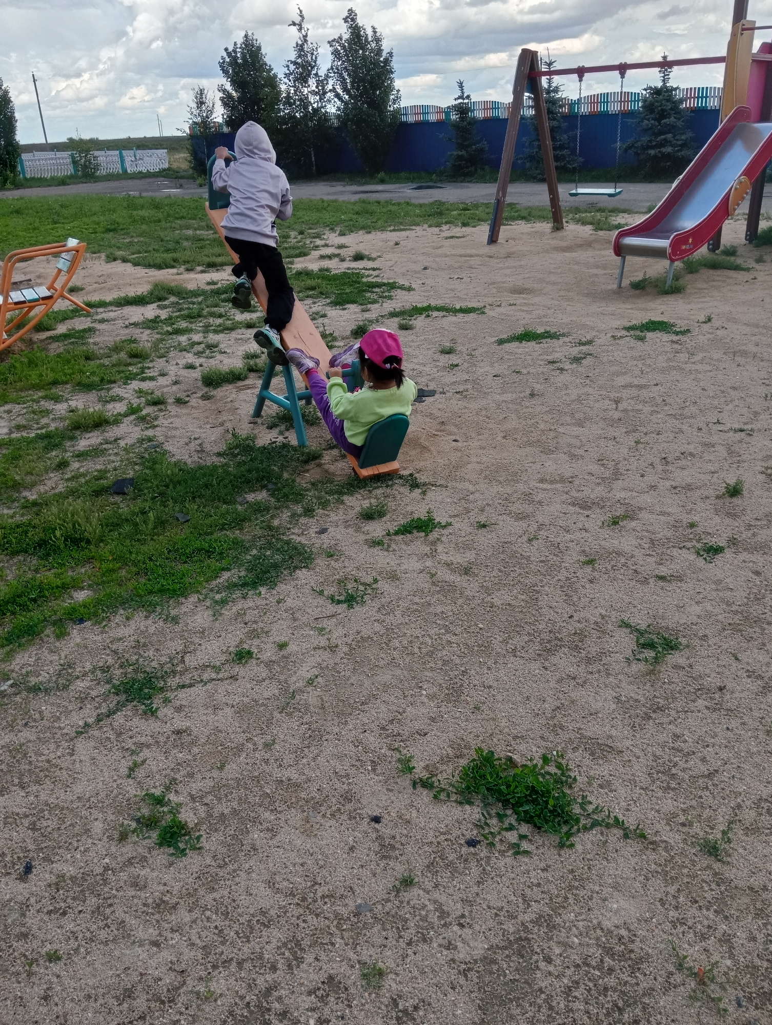 Children play in rural playground amid everyday community scenes