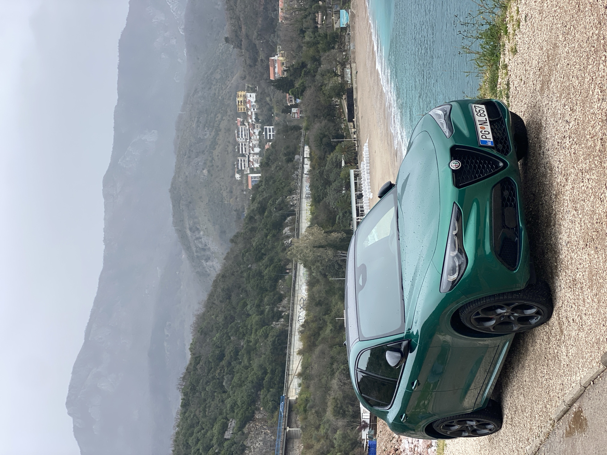 Green Alfa Romeo parked on gravel roadside in Montenegro