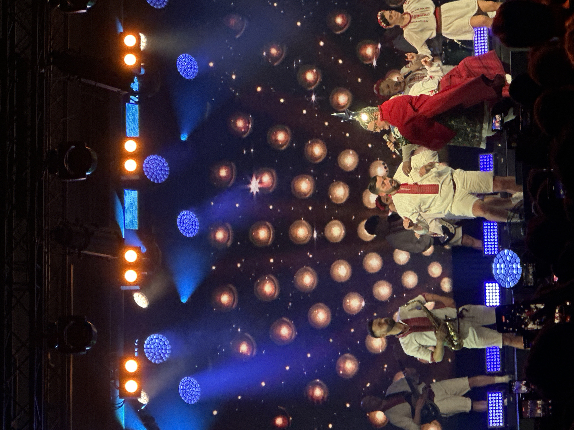 Music group performs at packed concert venue with elaborate lighting