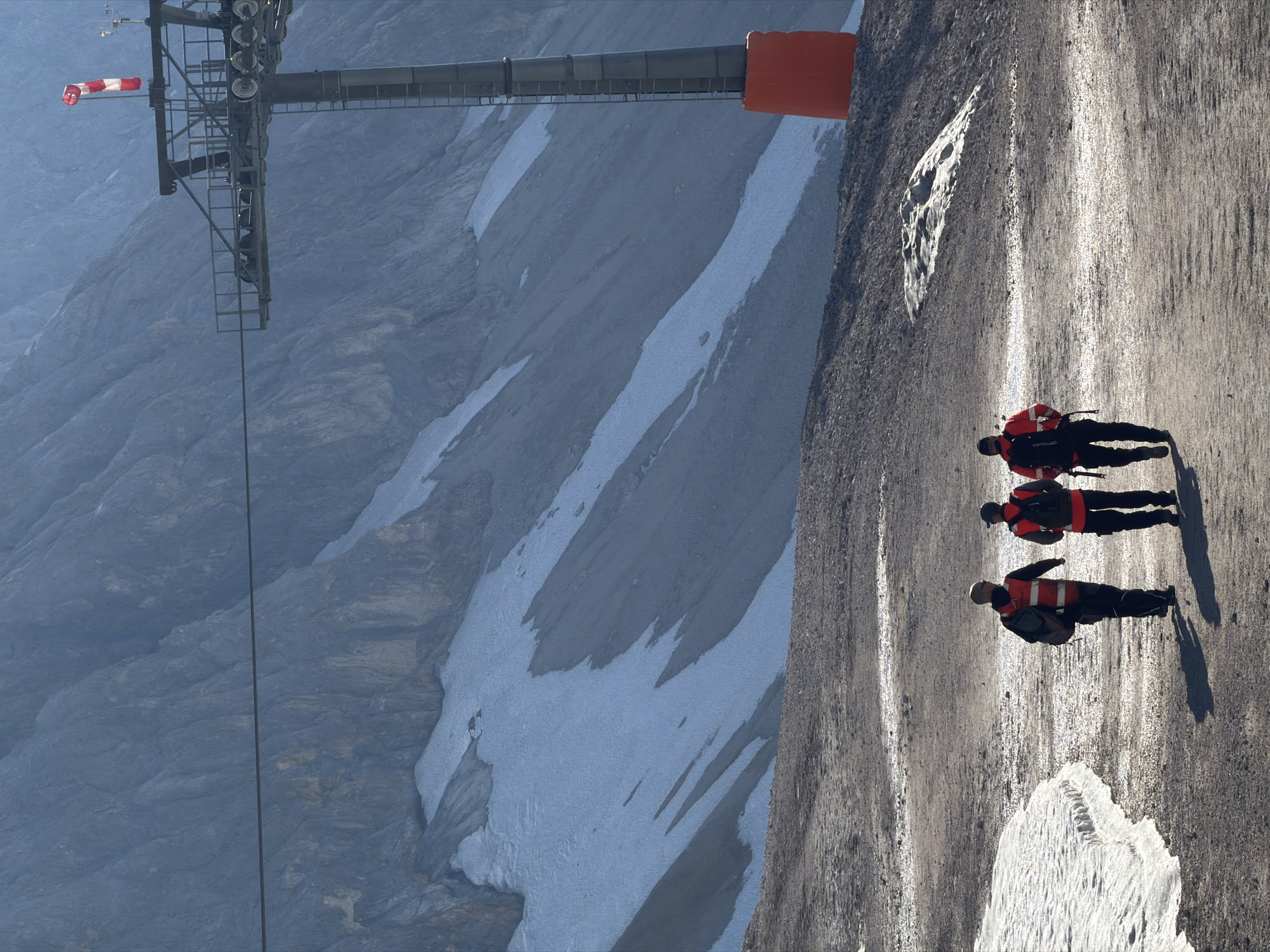 Early morning on the Zugspitze summit, hikers and snow groomers