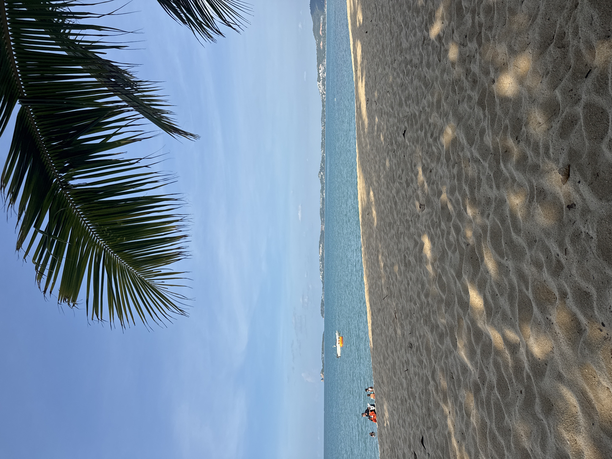 Sunny morning on a Ko Samui beach with boats and beachgoers