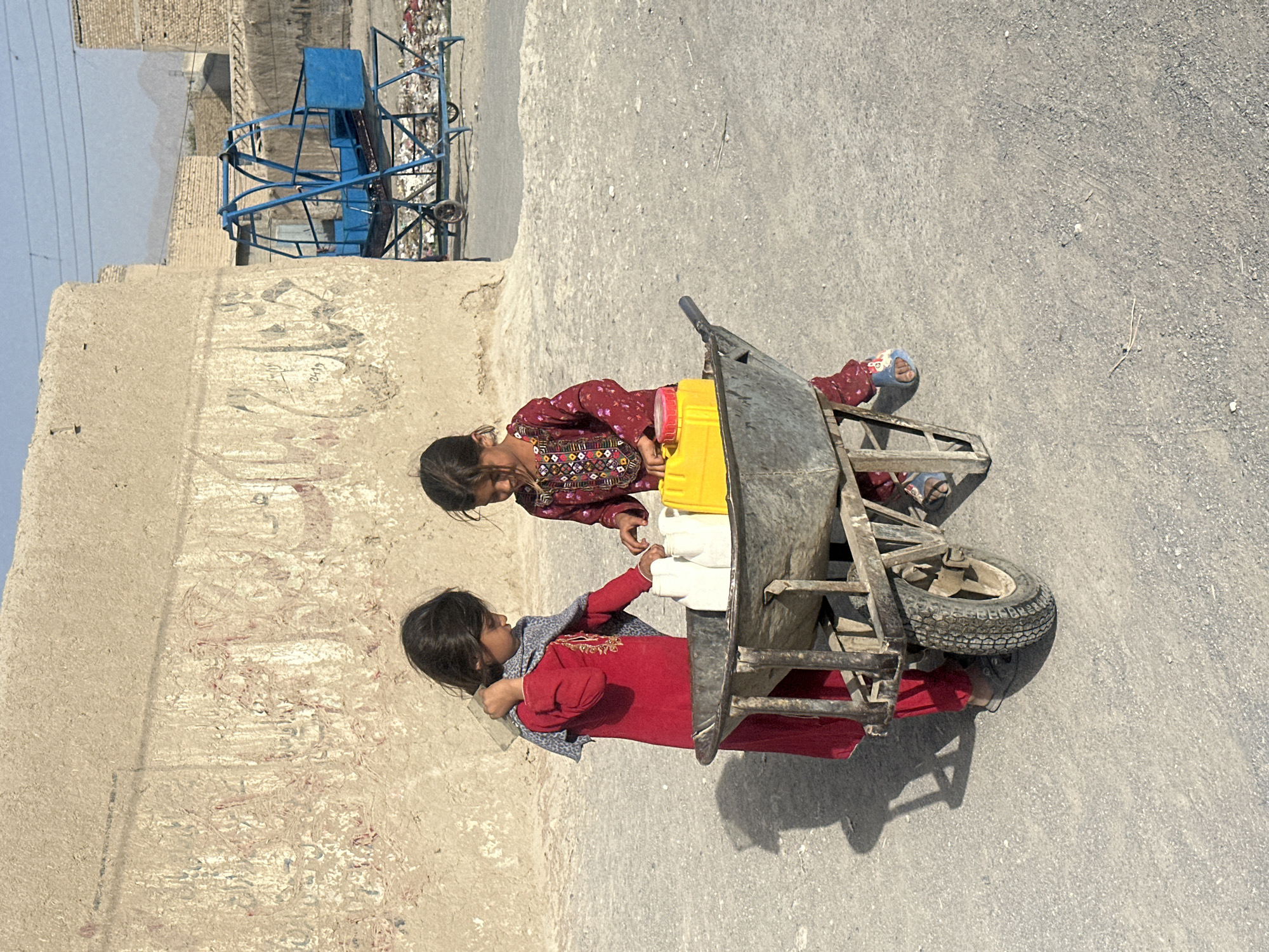Carrying containers in a dusty outdoor spot in Quetta