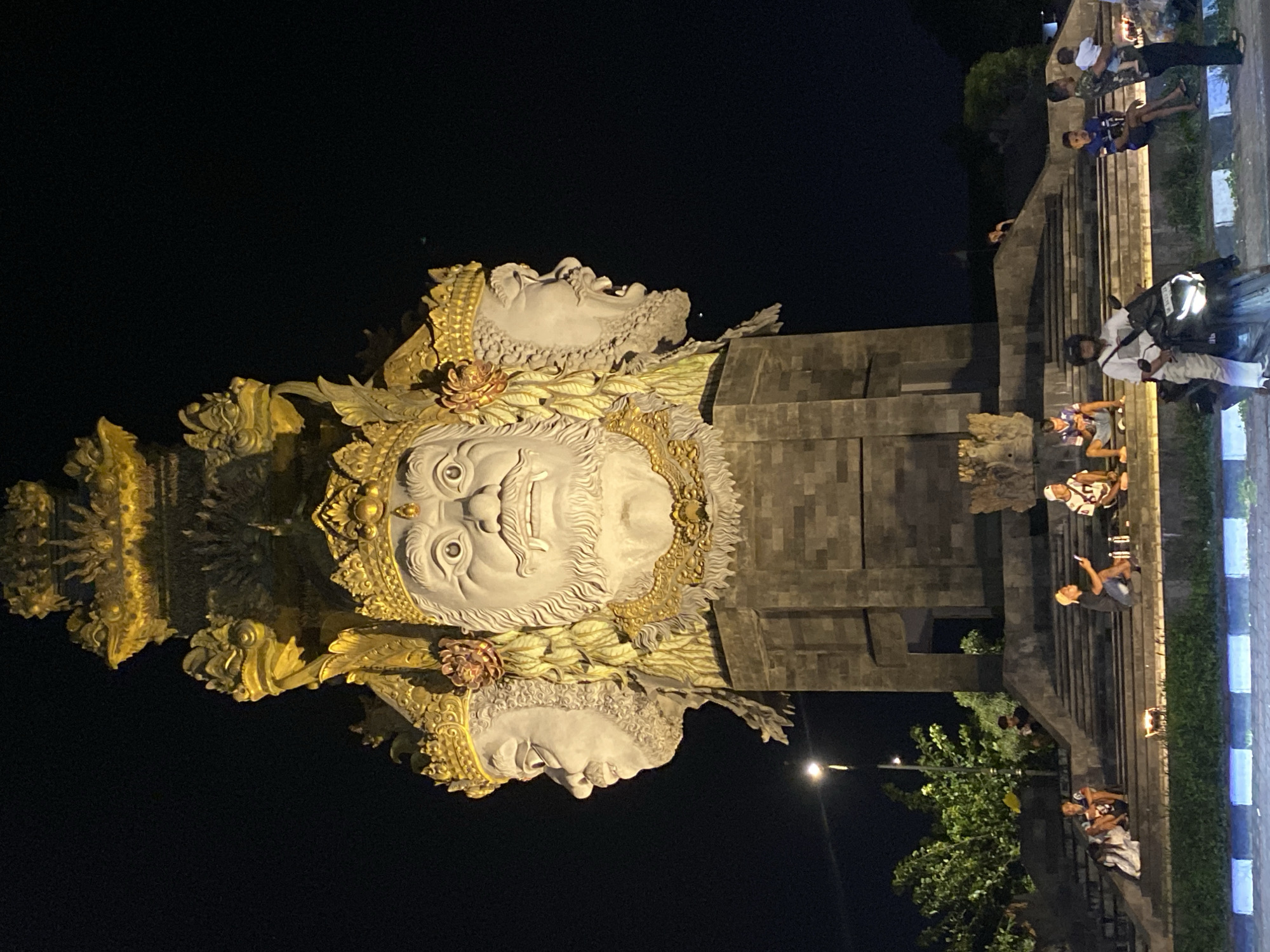 Ornate multi-faced statue illuminated at night in Denpasar