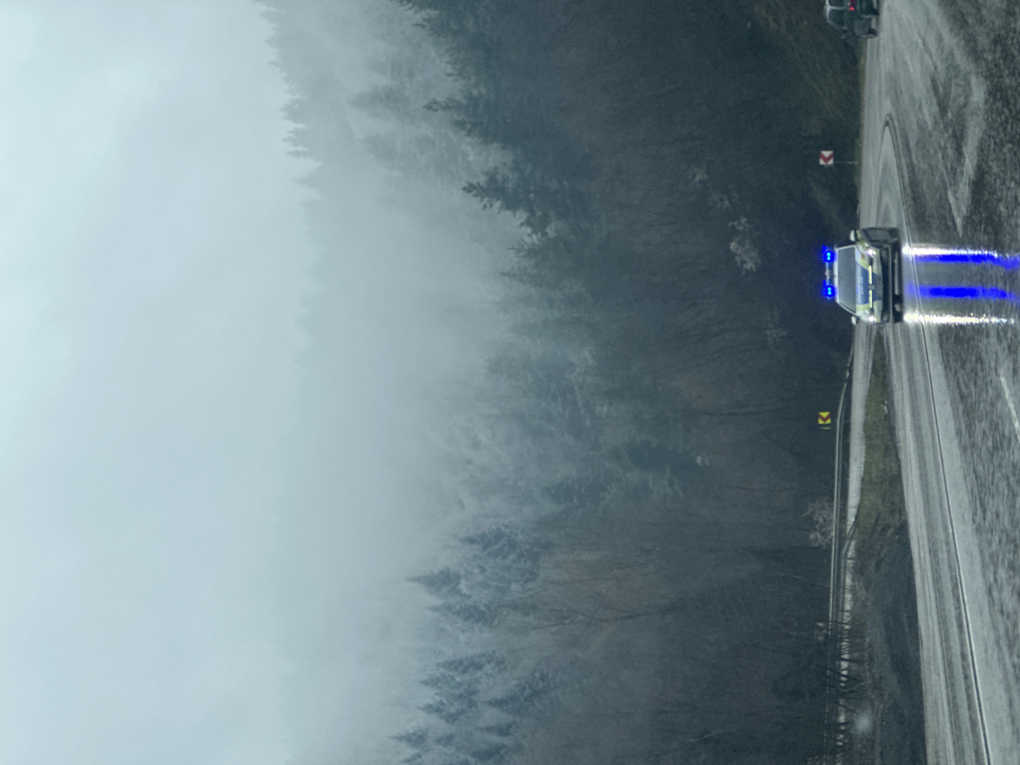 Police car travels wet Bulgarian road amid misty conditions