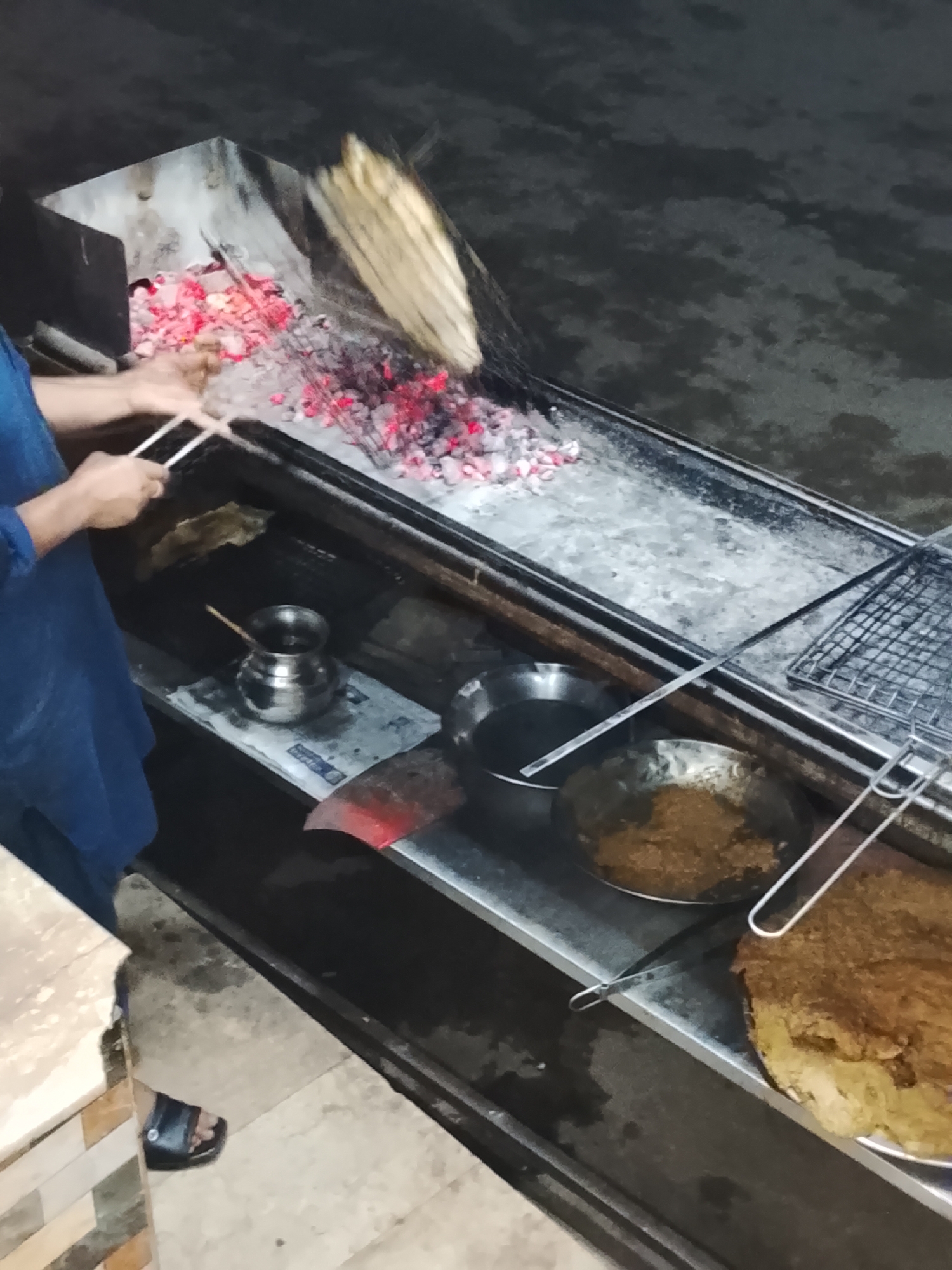 Street vendor cooks over charcoal grill in urban setting