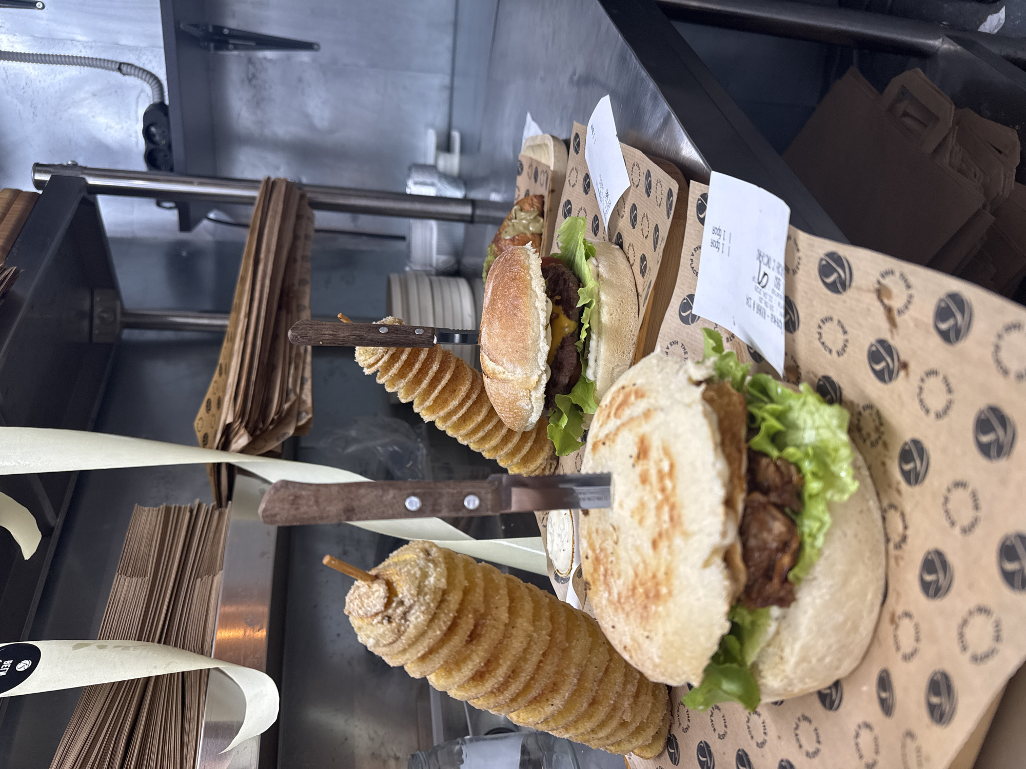 Hamburgers and spiral potatoes served with knives documented
