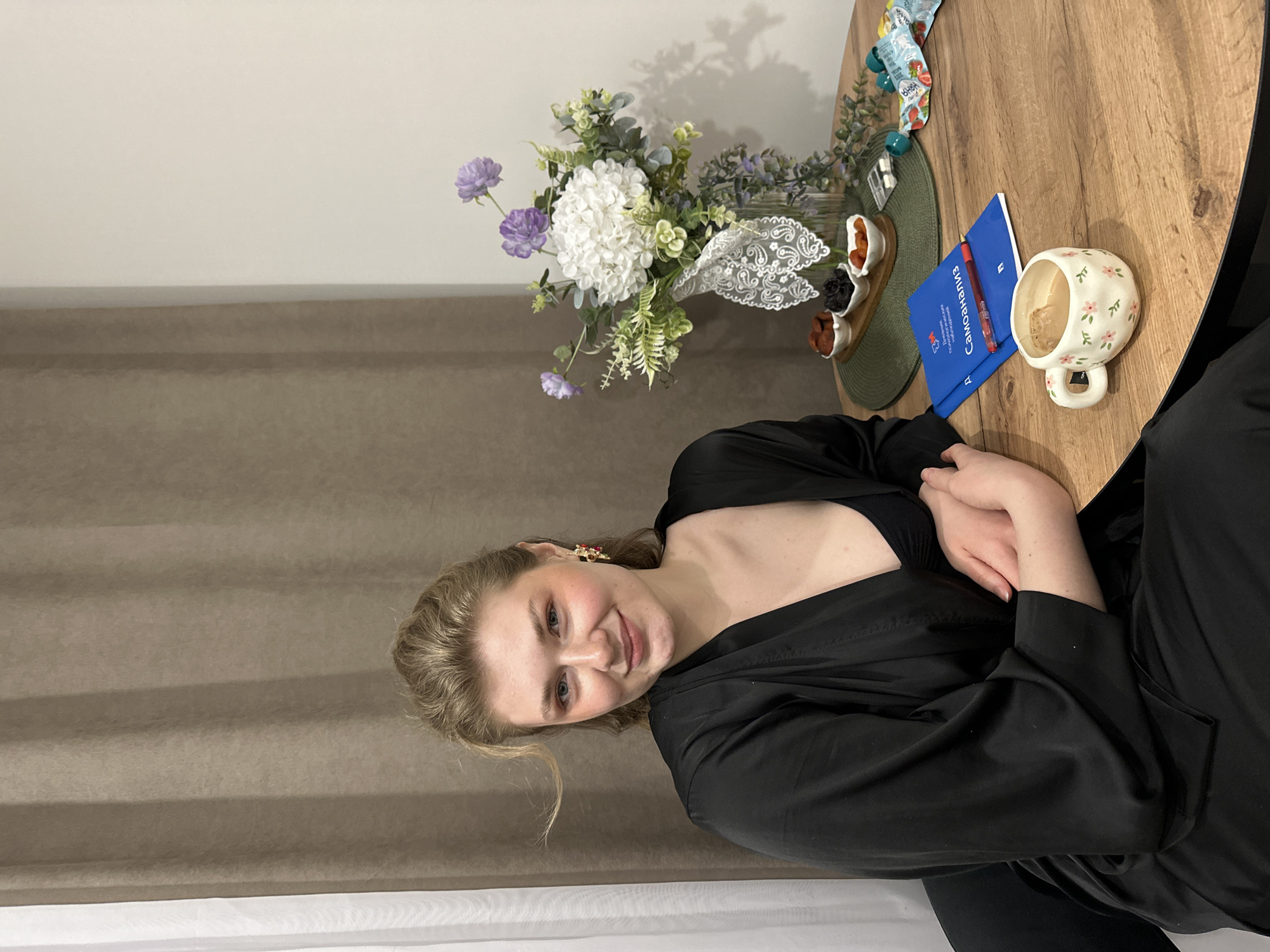 Woman at table with flowers, documents, and snacks