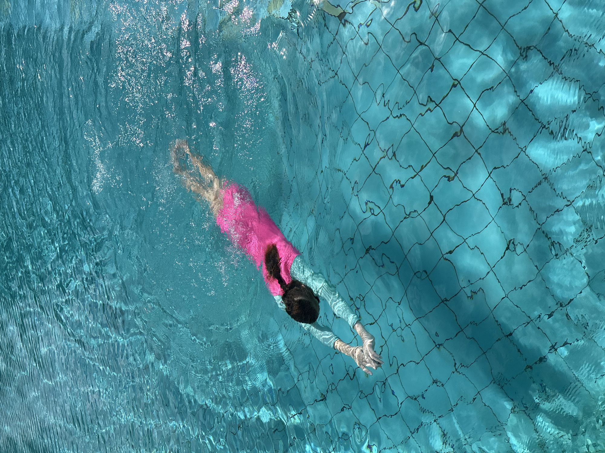 Children swim at Chalong resort pool during early morning hours