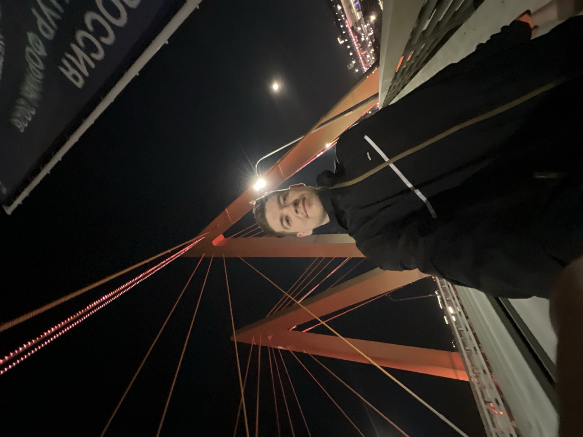 Man films nighttime selfies on illuminated Millennium Bridge in Kazan