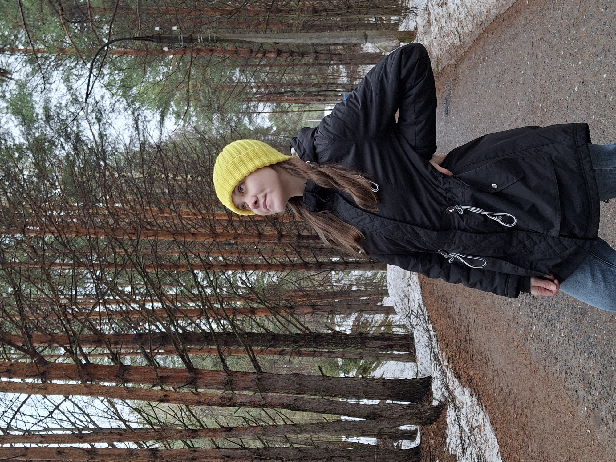 Woman walks forest path amid spring snow in Chaikovsky