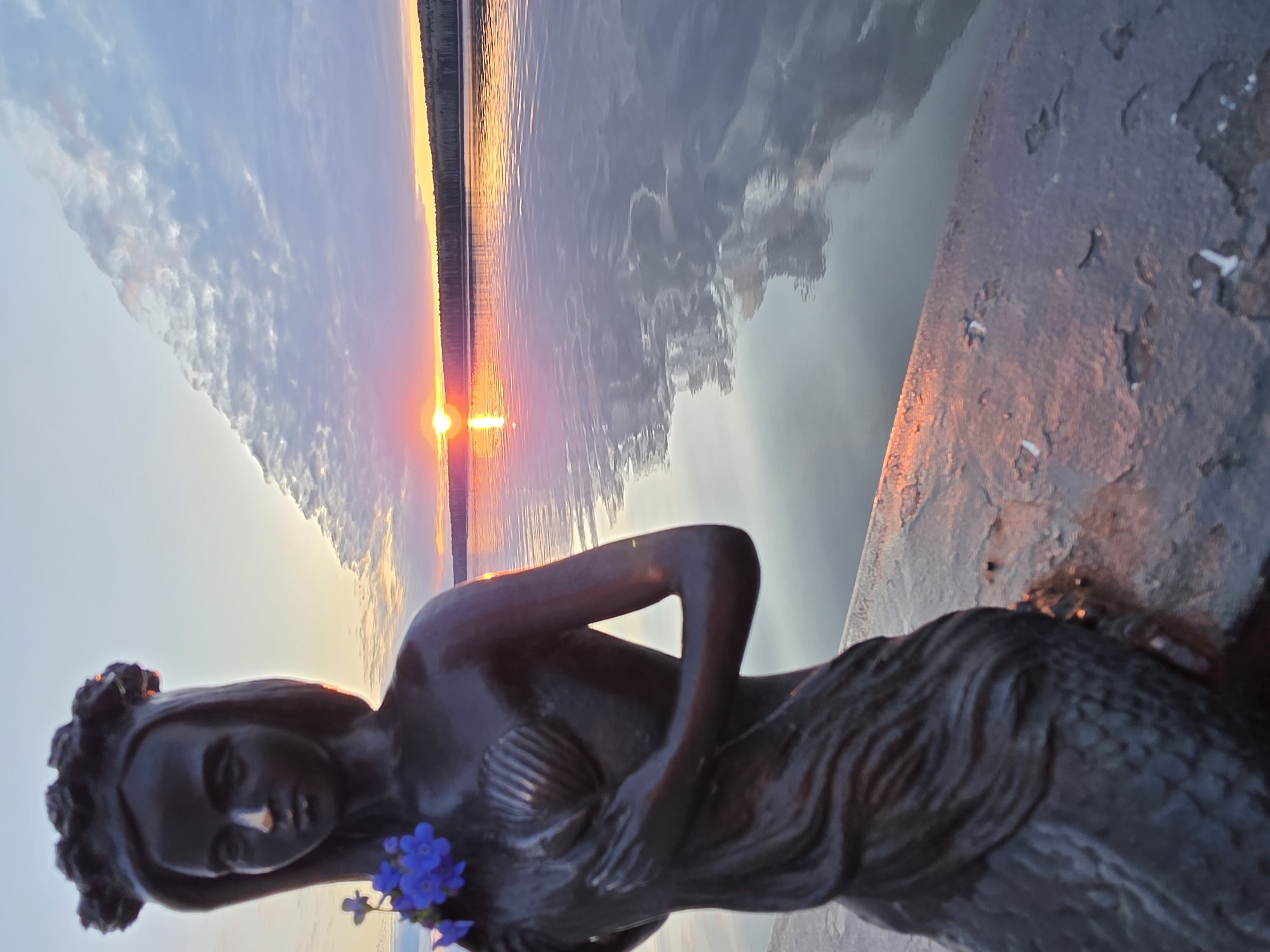 Sunset celebration documented at Chaikovsky waterfront with flowers, statue