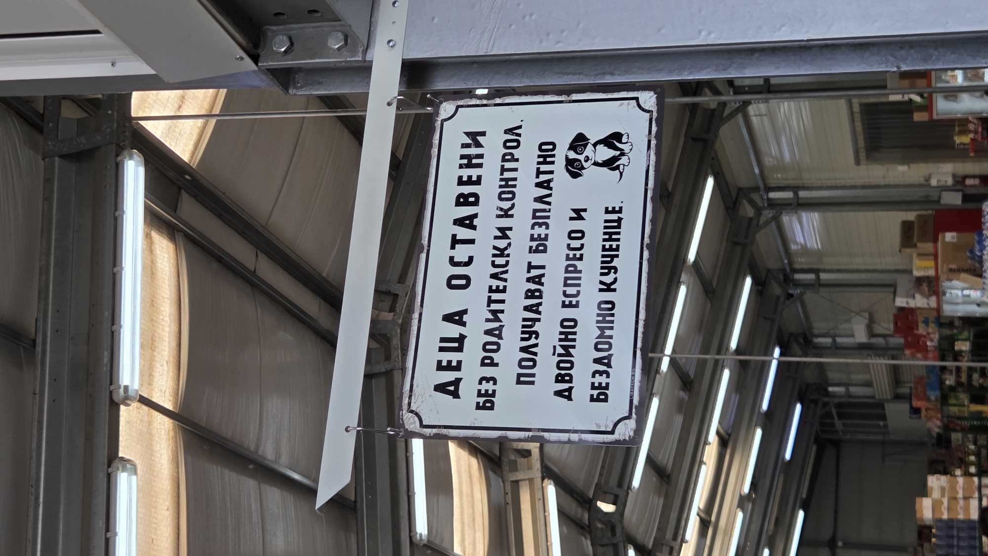 Dog-illustrated sign hangs inside a fluorescent-lit indoor space
