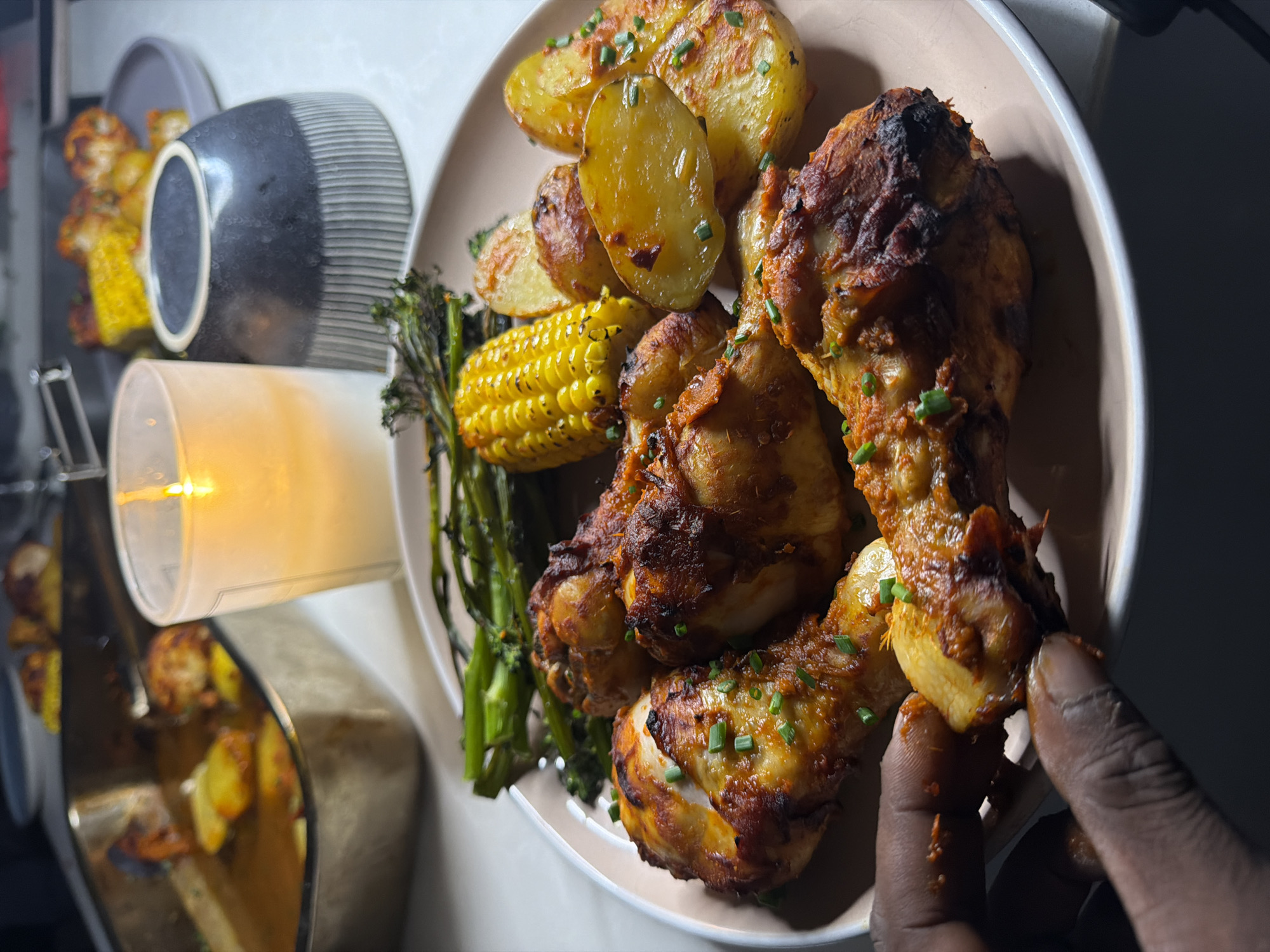Hand reaches for chicken drumstick at dinner