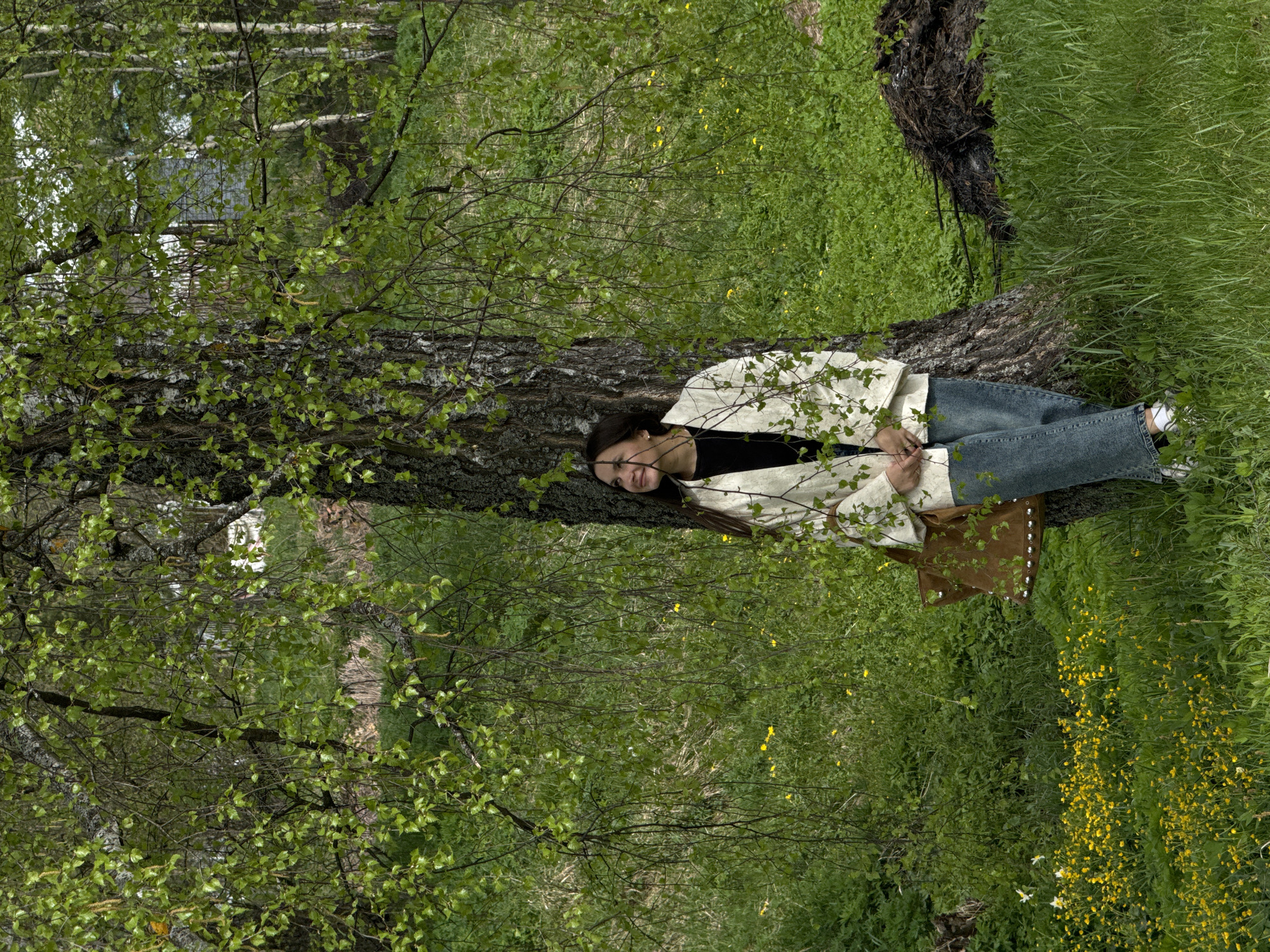 Woman rests against birch tree in Russian countryside