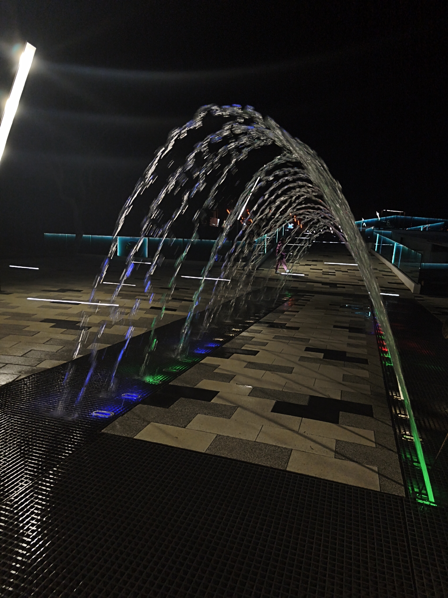 Evening visitors experience illuminated fountain walkway in Russian coastal cities