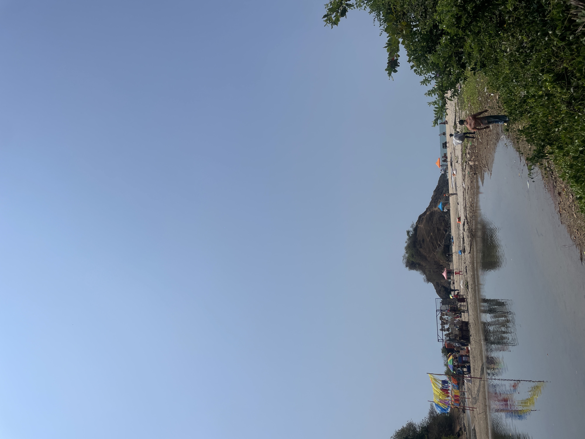 People gather at sandy shoreline in Bhogave, India