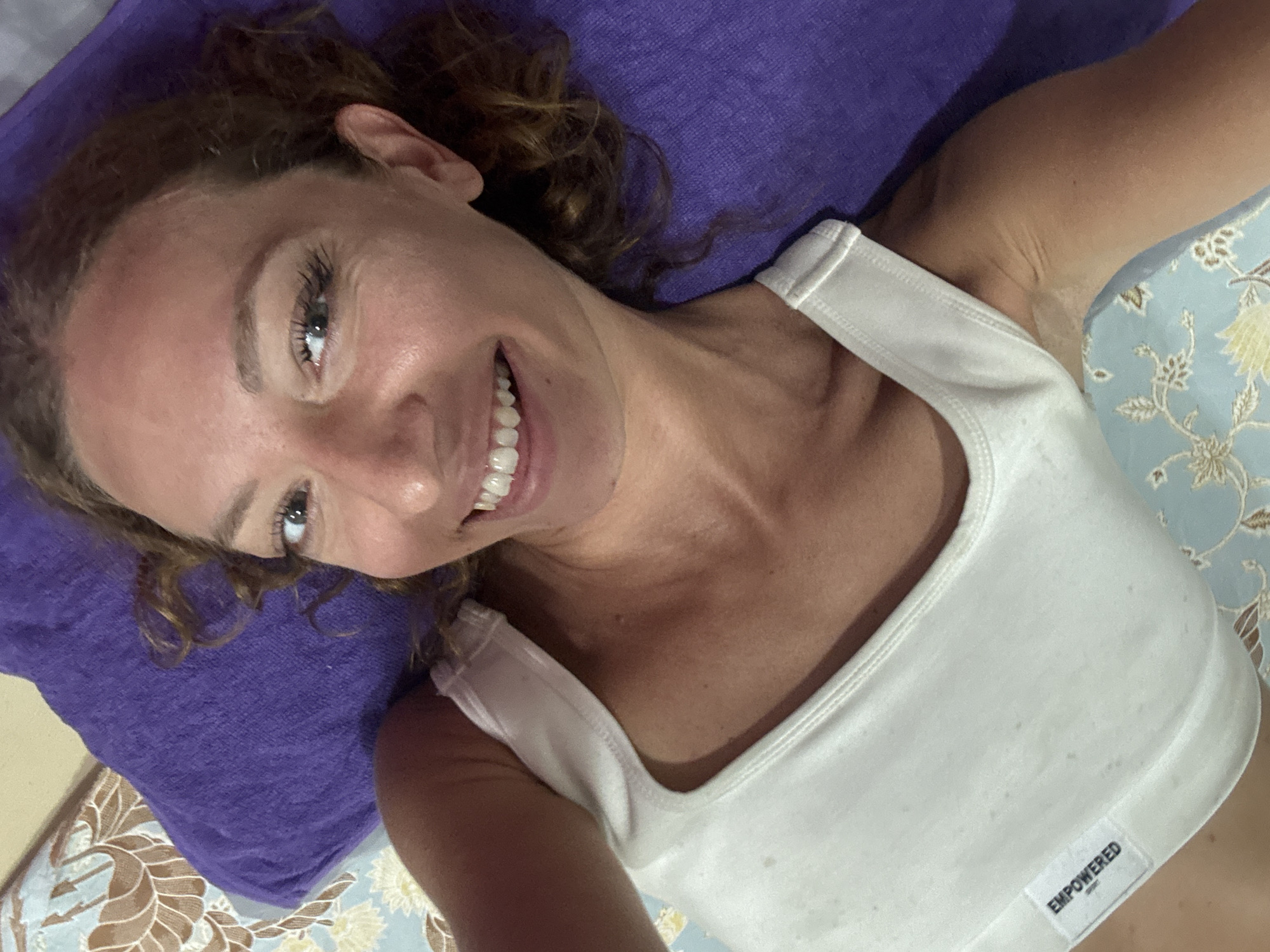 Woman in 'EMPOWERED' tank top photographed smiling in Thailand
