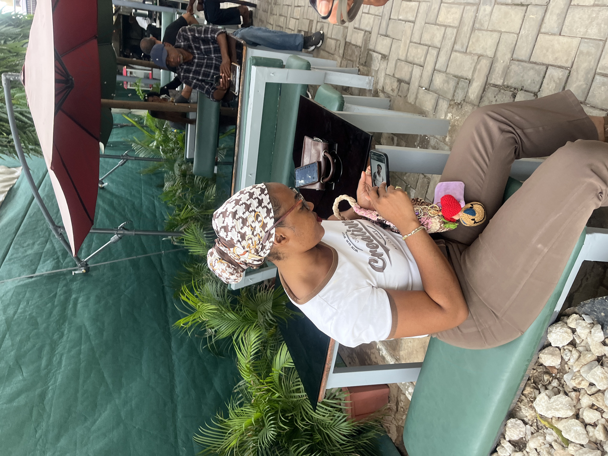 Woman uses smartphone at outdoor cafe in Karum, Nigeria