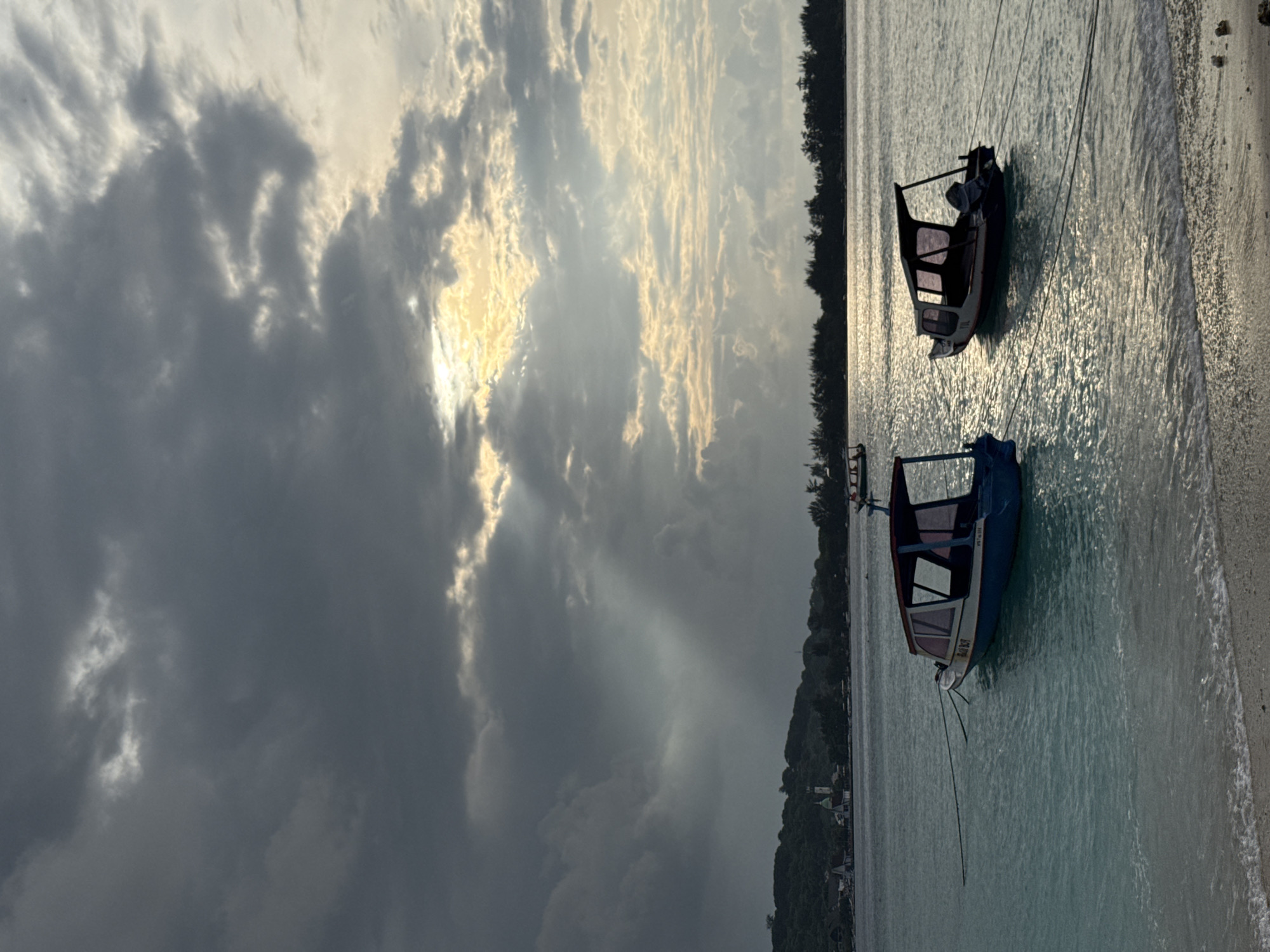 Two boats beached on Indonesian shore under cloudy skies