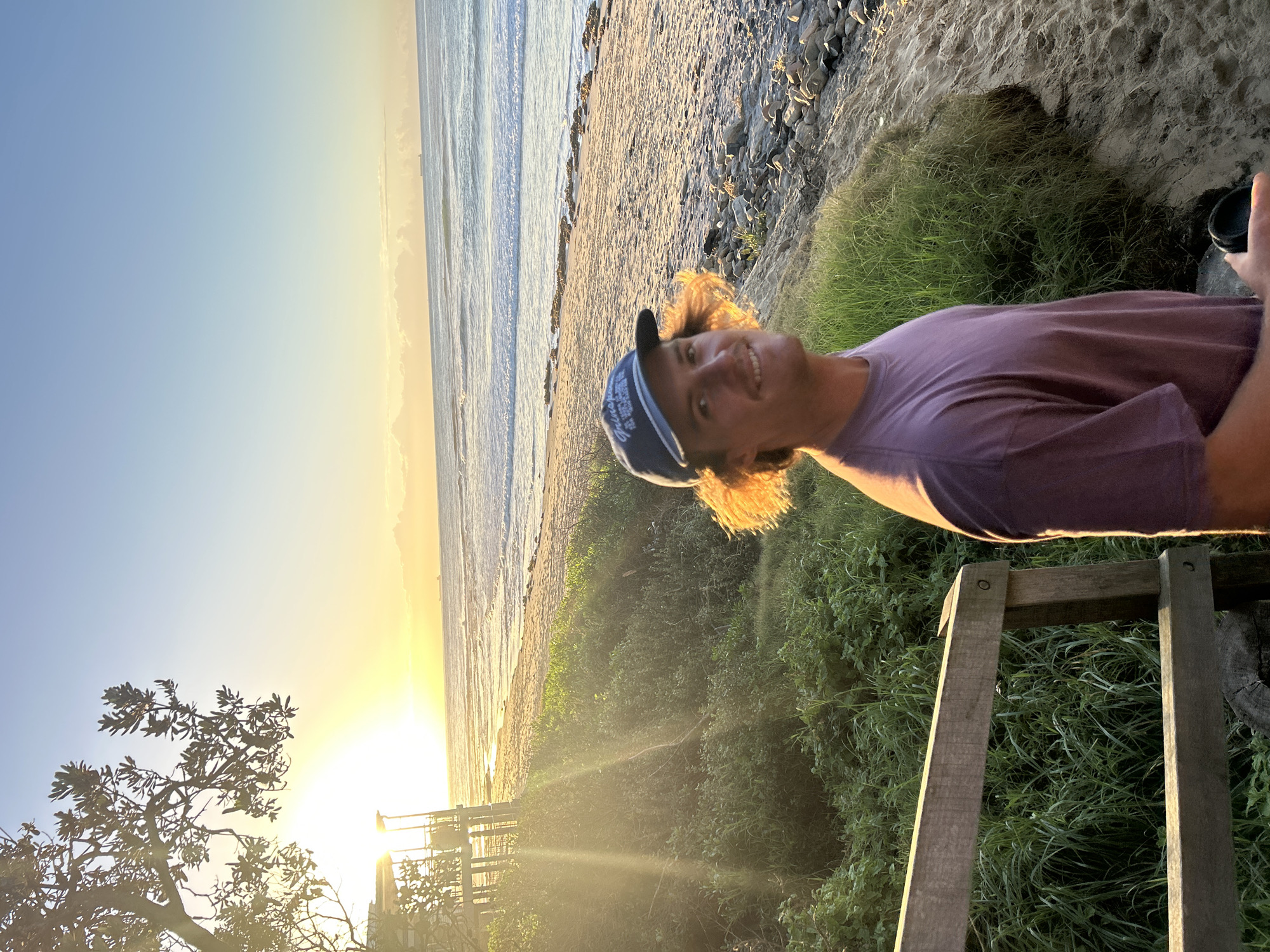 Young man poses at beach dunes during golden hour