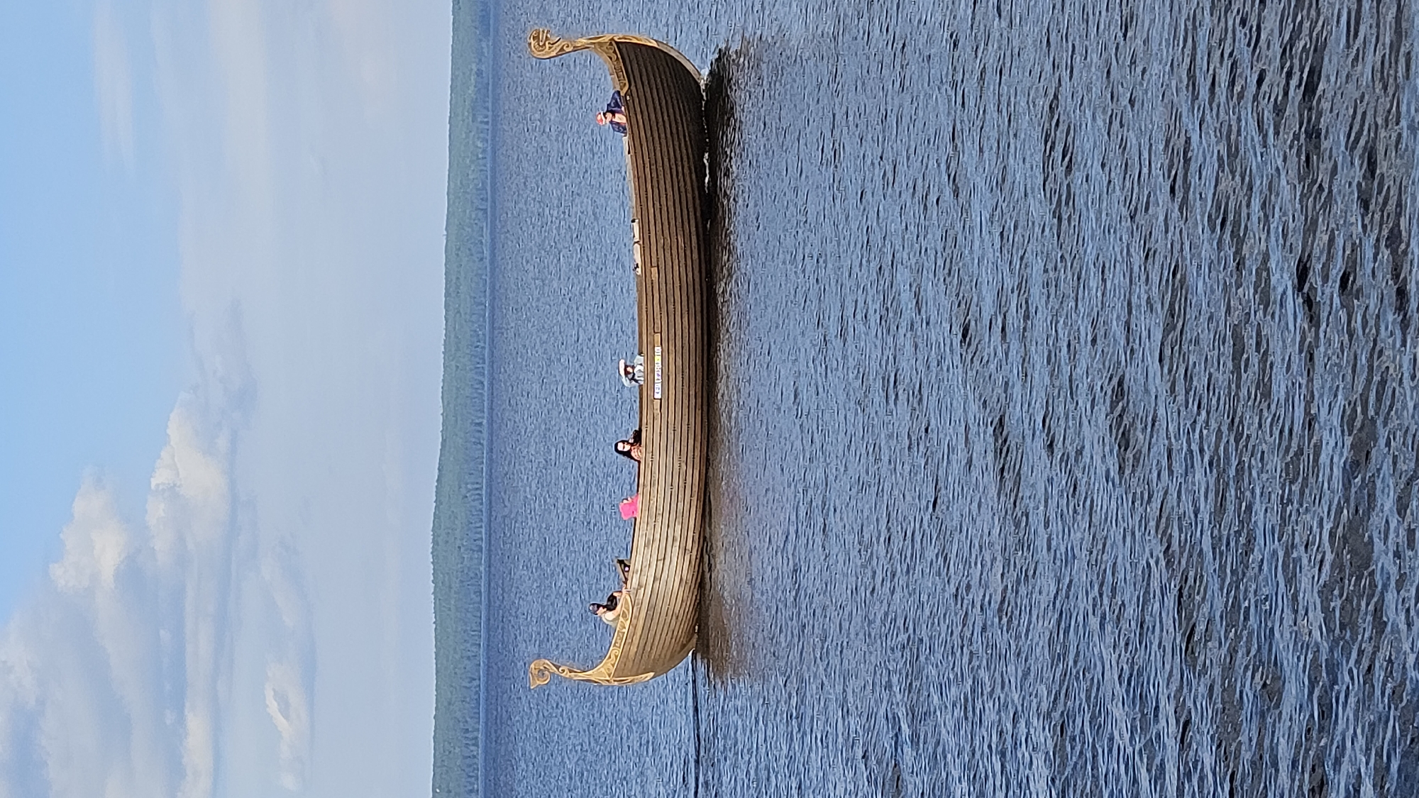 Sunny day at a waterfront park with Viking boats and kvas
