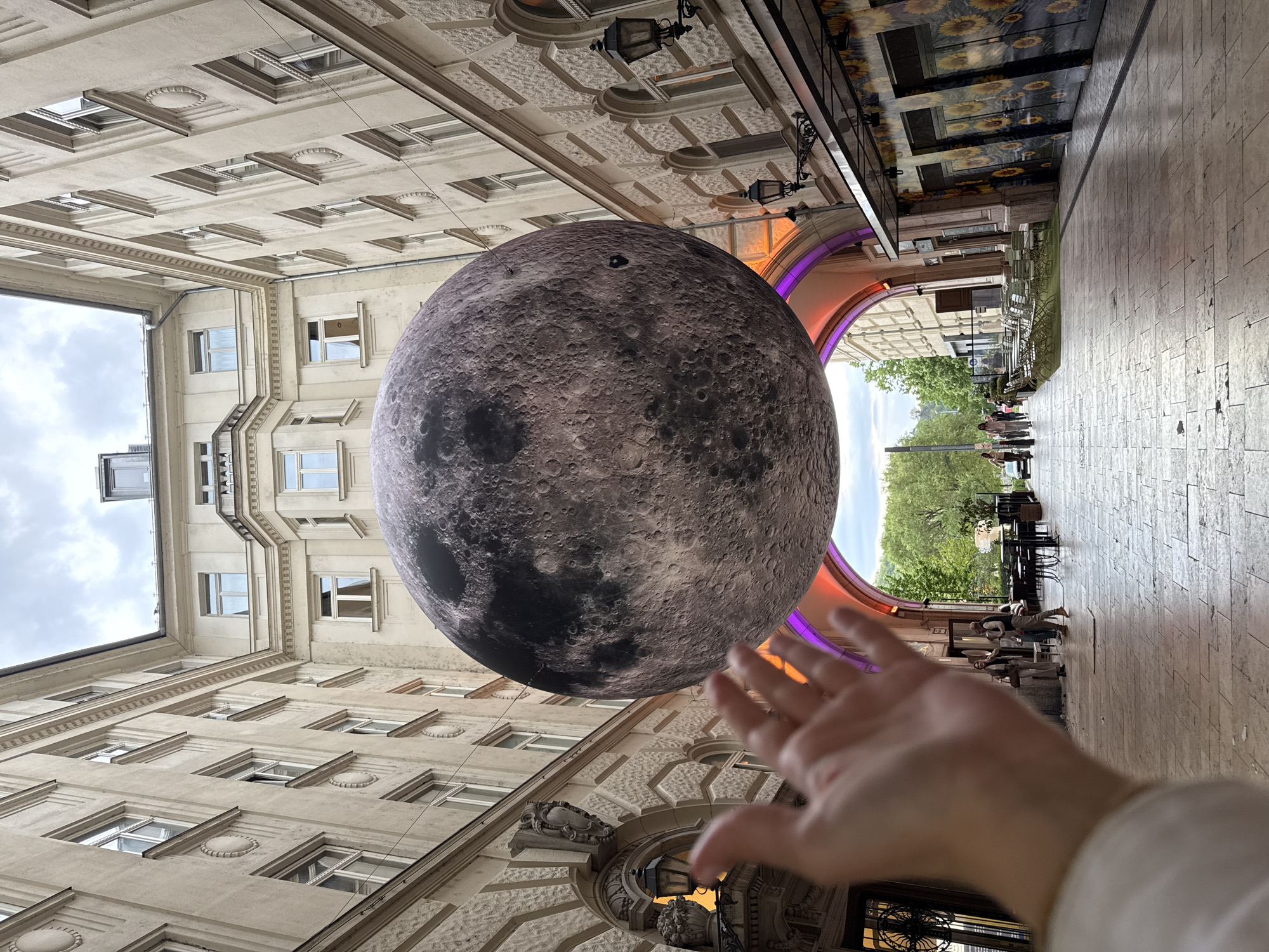 Moon art installation suspended between historic Budapest buildings