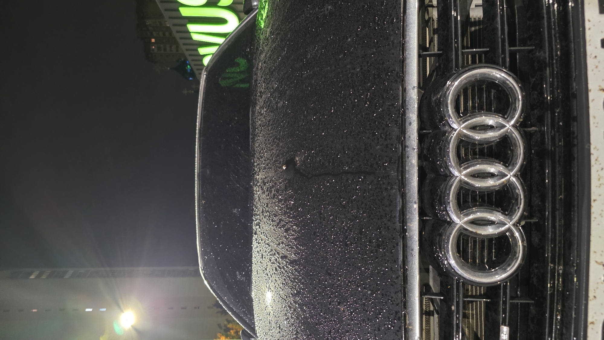 Rain-soaked luxury cars photographed in nighttime urban setting