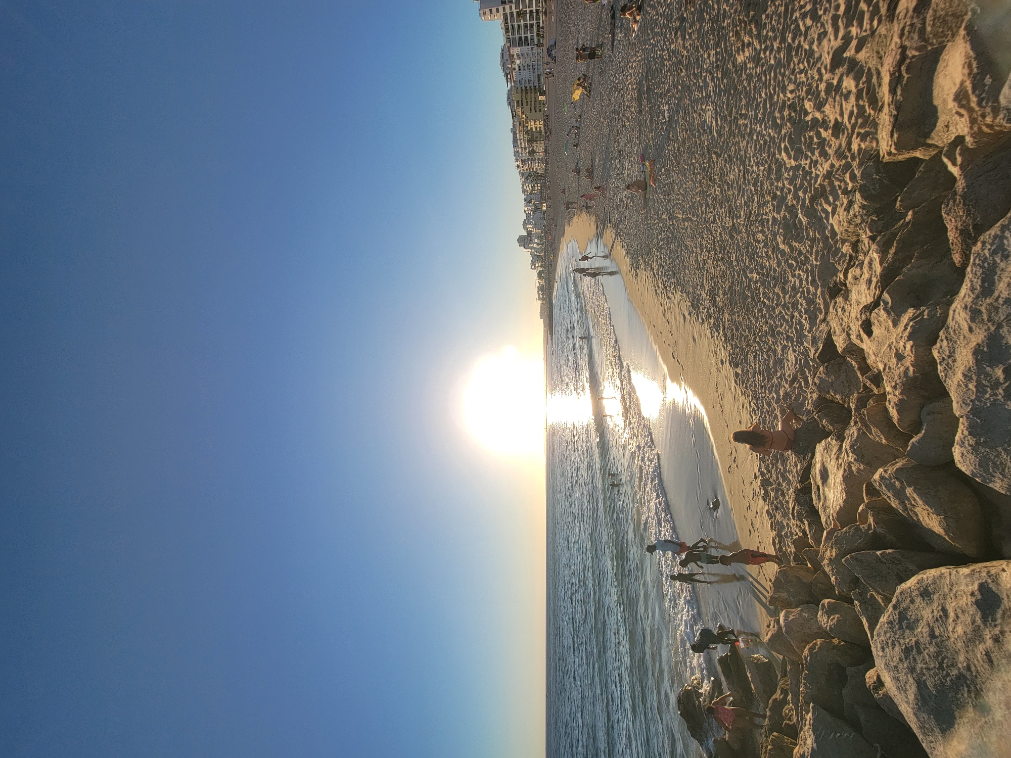 Sun low over Quarteira's coastline, ocean reflecting the light