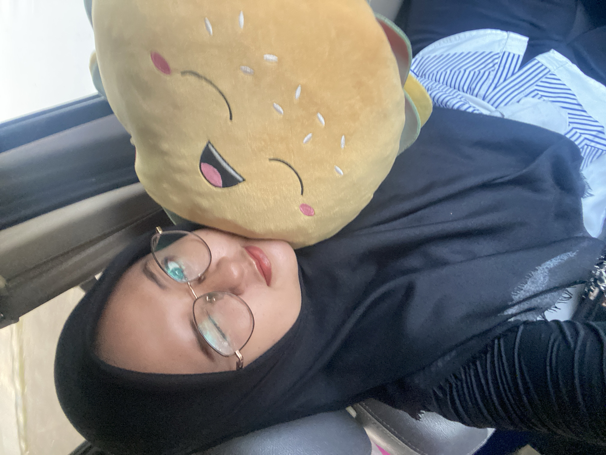 Woman rests with hamburger plush toy in Boro, Indonesia
