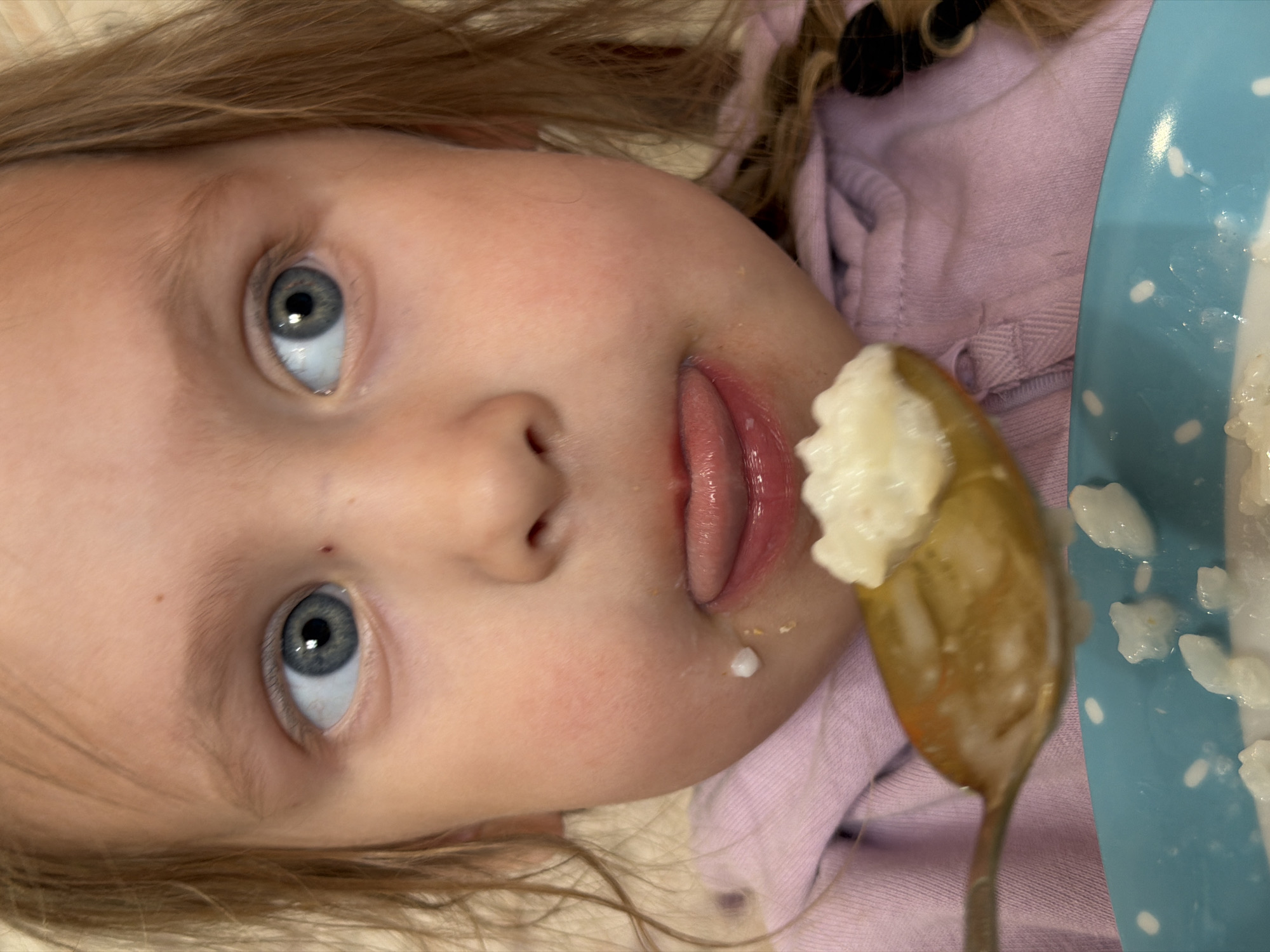 Young girl enjoys breakfast rice pudding in Chaikovsky, Russia