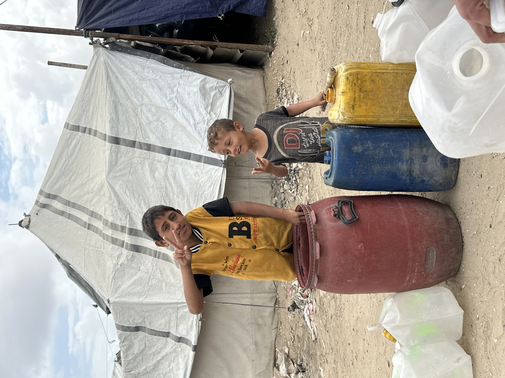 Children gather near water containers in Gaza refugee camp