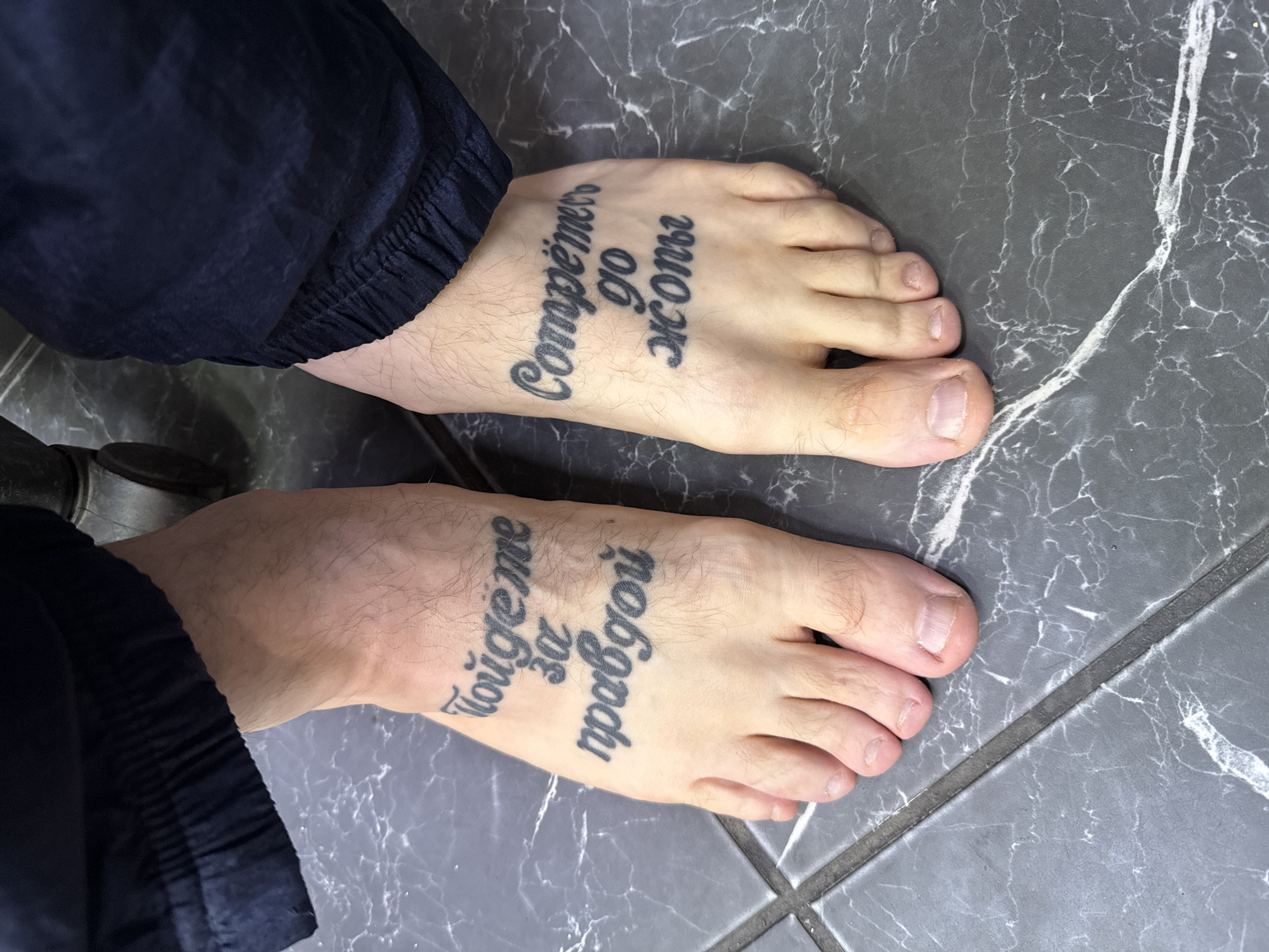 Tattooed feet photographed on marble floor in Moscow