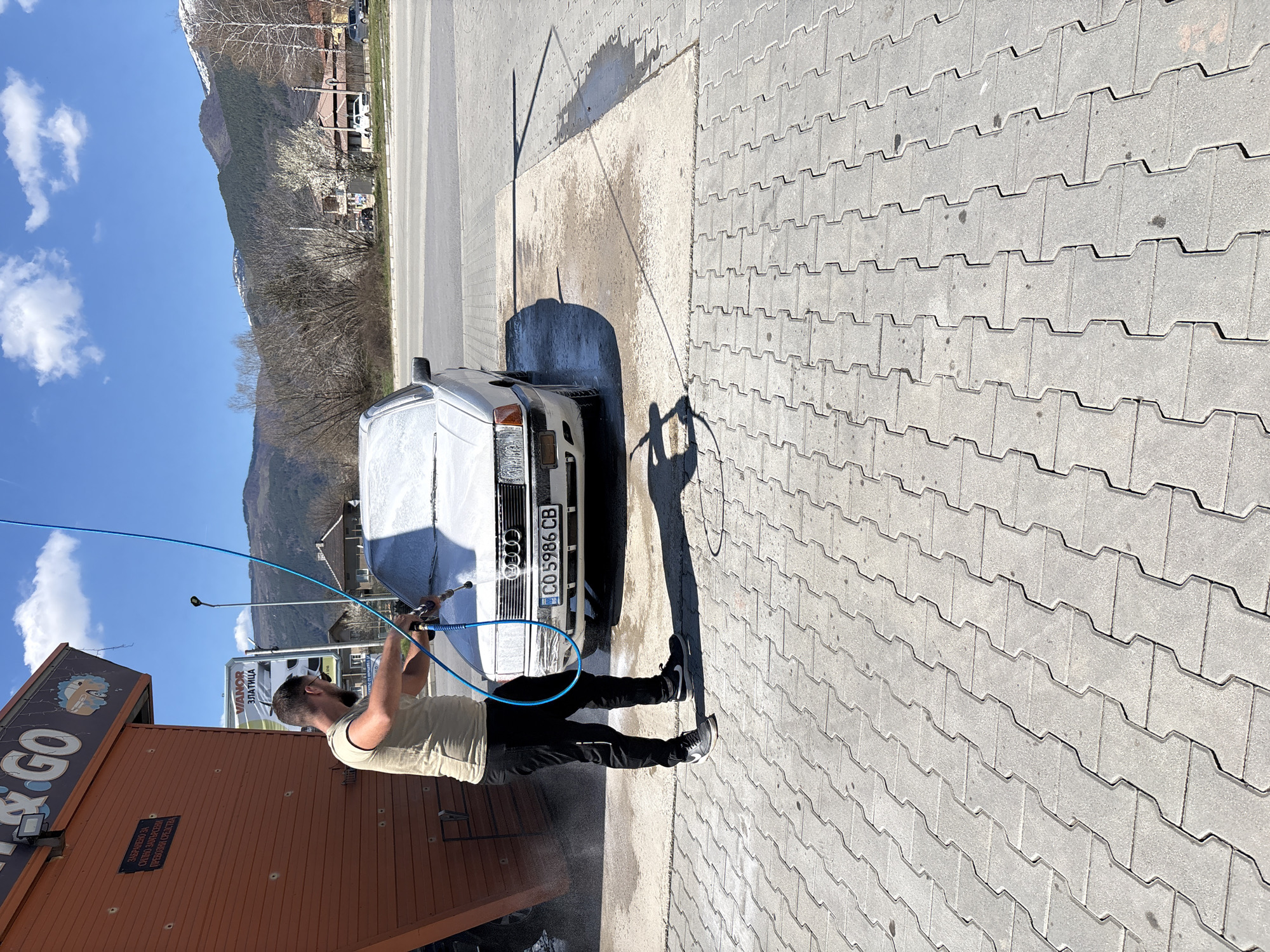 Man washes white sedan at Zlatitsa car wash facility