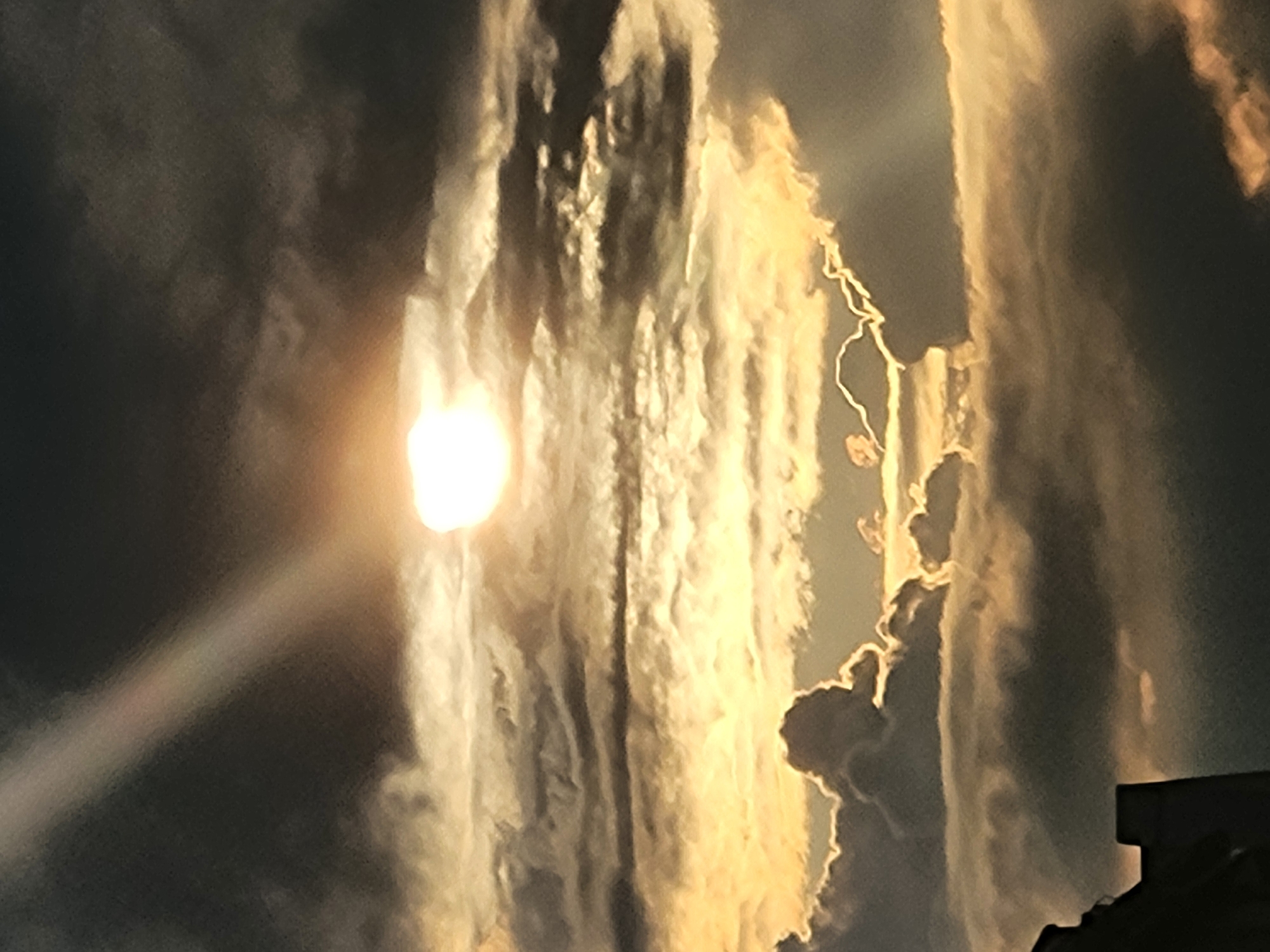 Sun breaks through dramatic clouds over a residential street at sunset