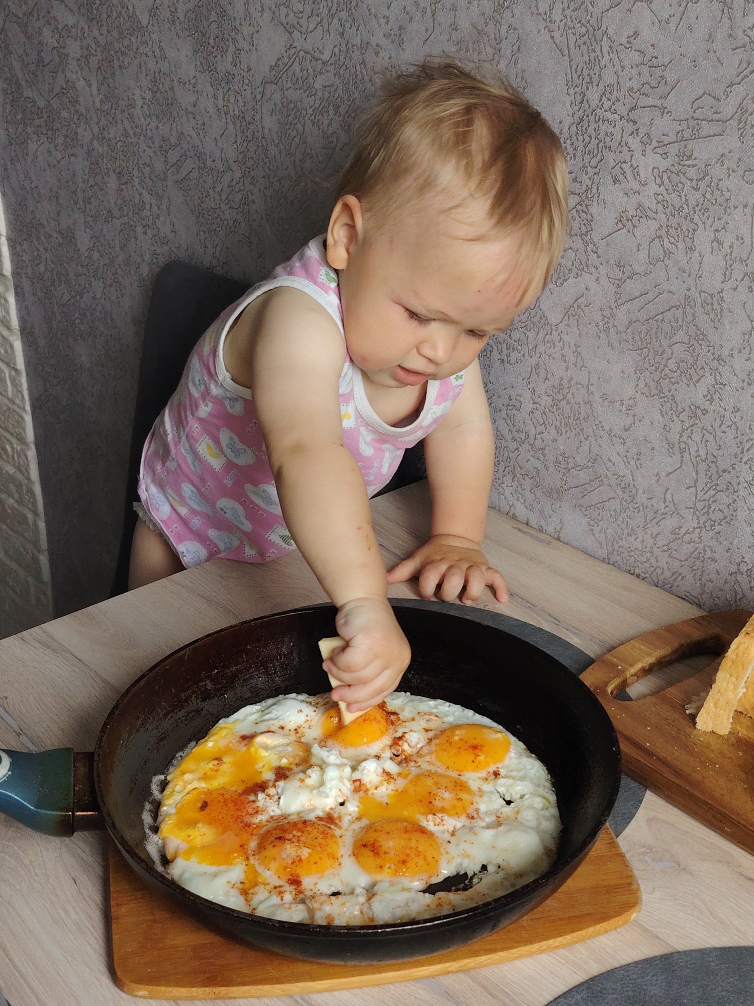 Toddler prepares breakfast with adult assistance in Chaikovsky kitchen