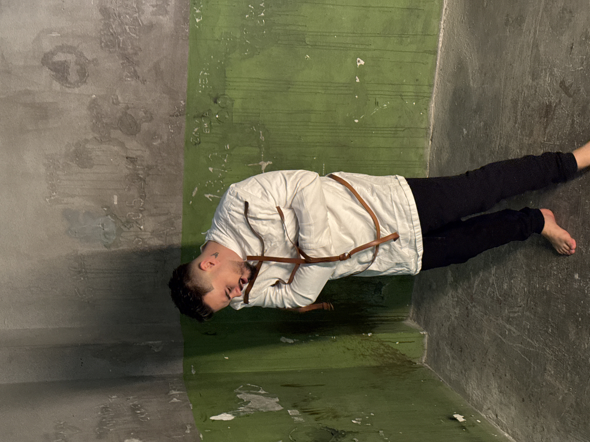 Man in straitjacket filmed in dilapidated Sofia room