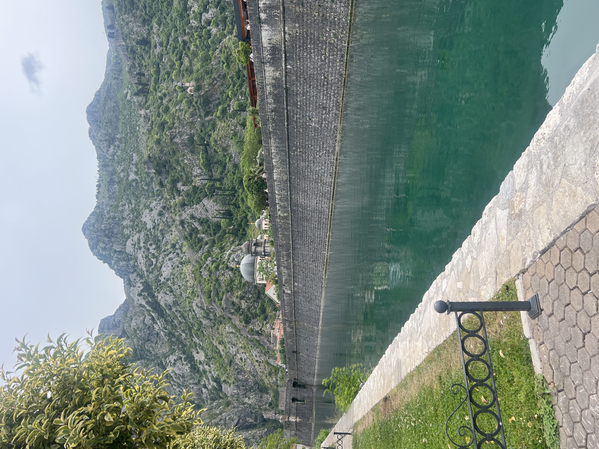 Visitor documents historic Kotor waterfront and stone fortifications