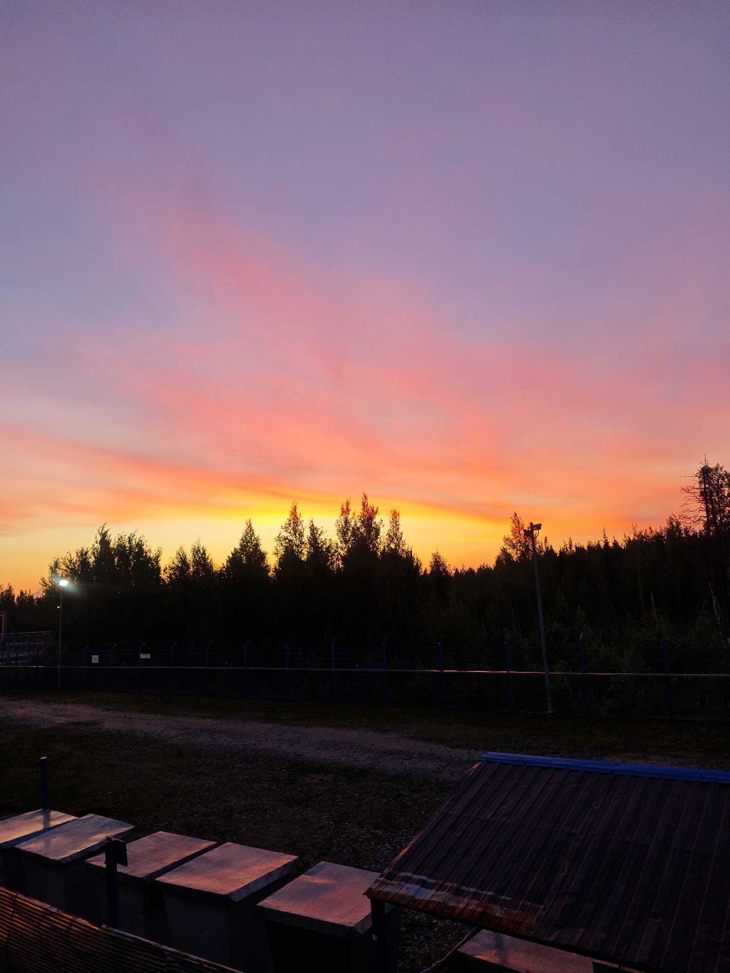 Gas flare burns at dusk over an industrial facility