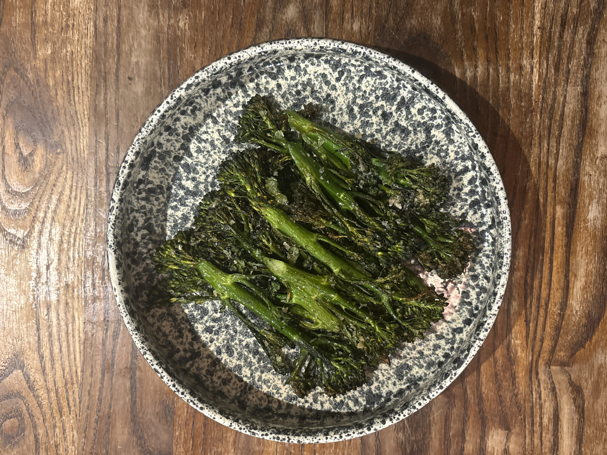 Cooked broccolini served on speckled ceramic plate in London