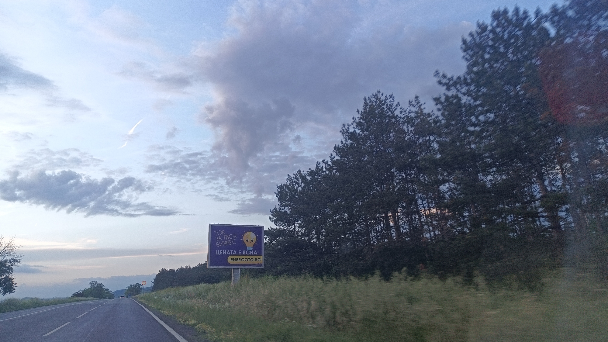 Vehicle travels Bulgarian road under blue sky