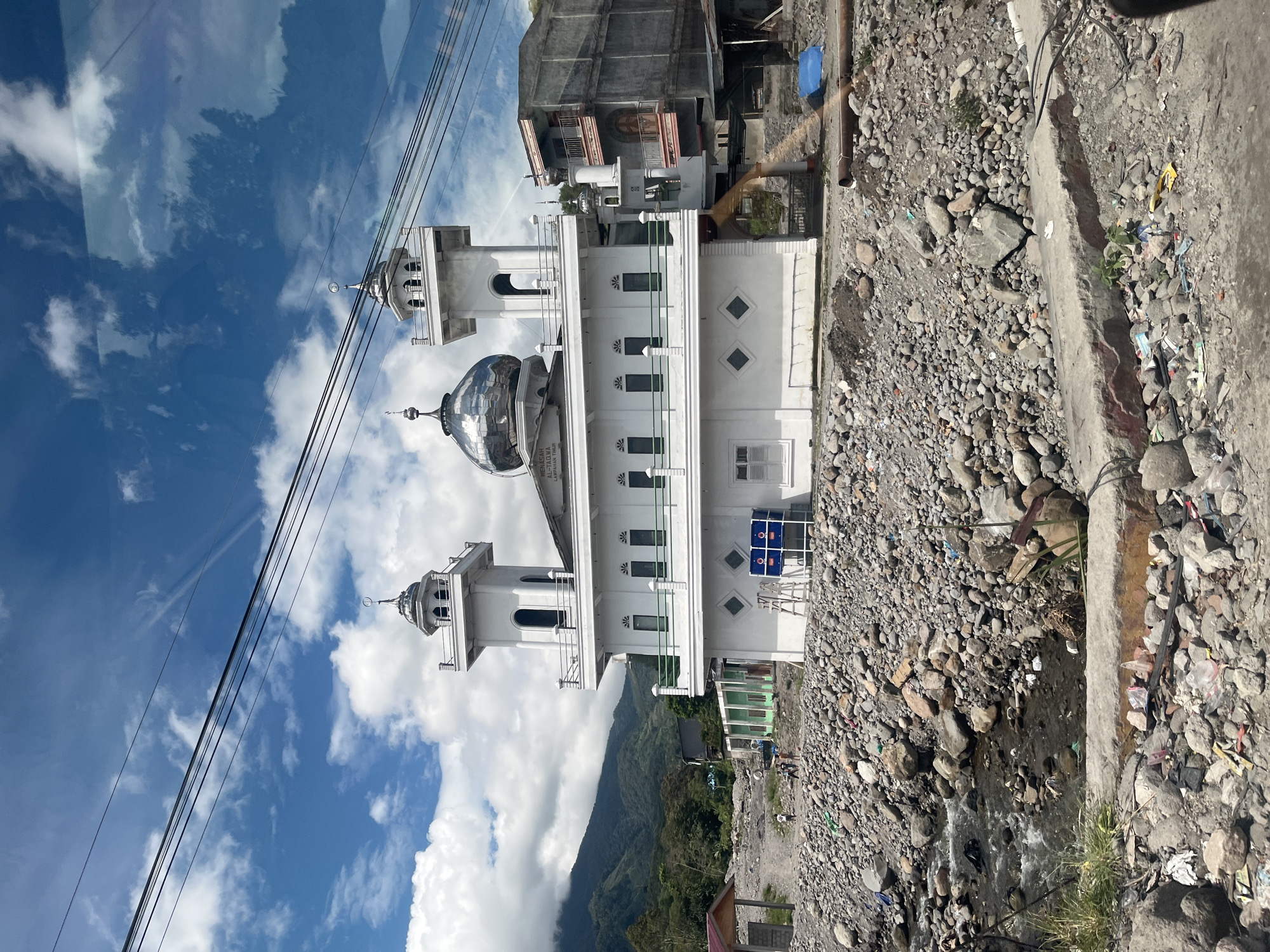 White mosque with twin minarets overlooks rocky stream in Simpanglayang