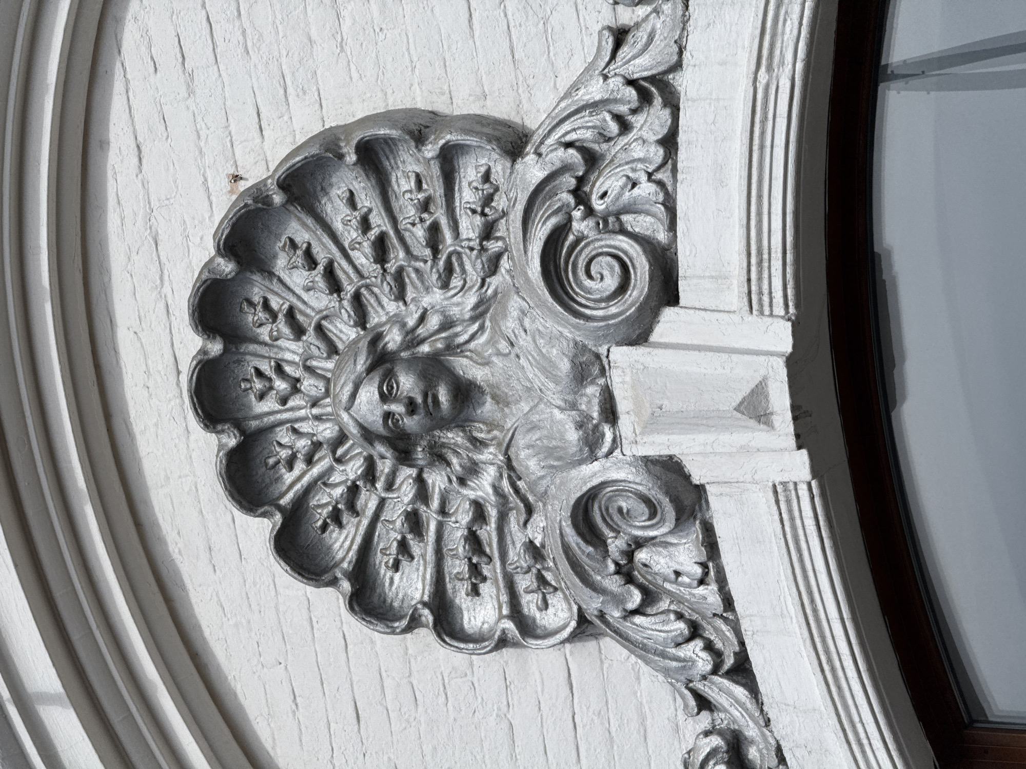 Ornate facial motif spotted on white brick architecture