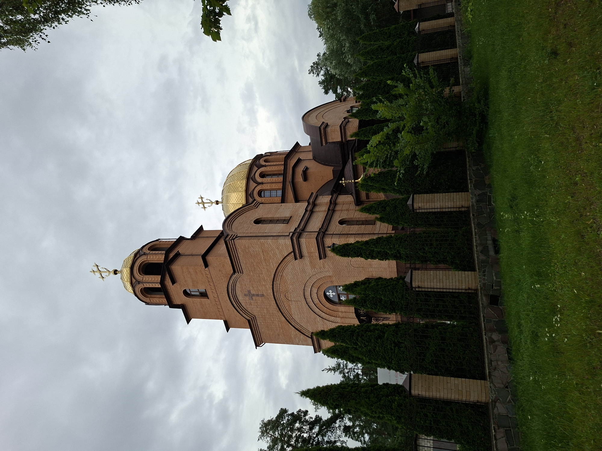 Kyiv church, shoreline, and park sculptures on a cloudy afternoon