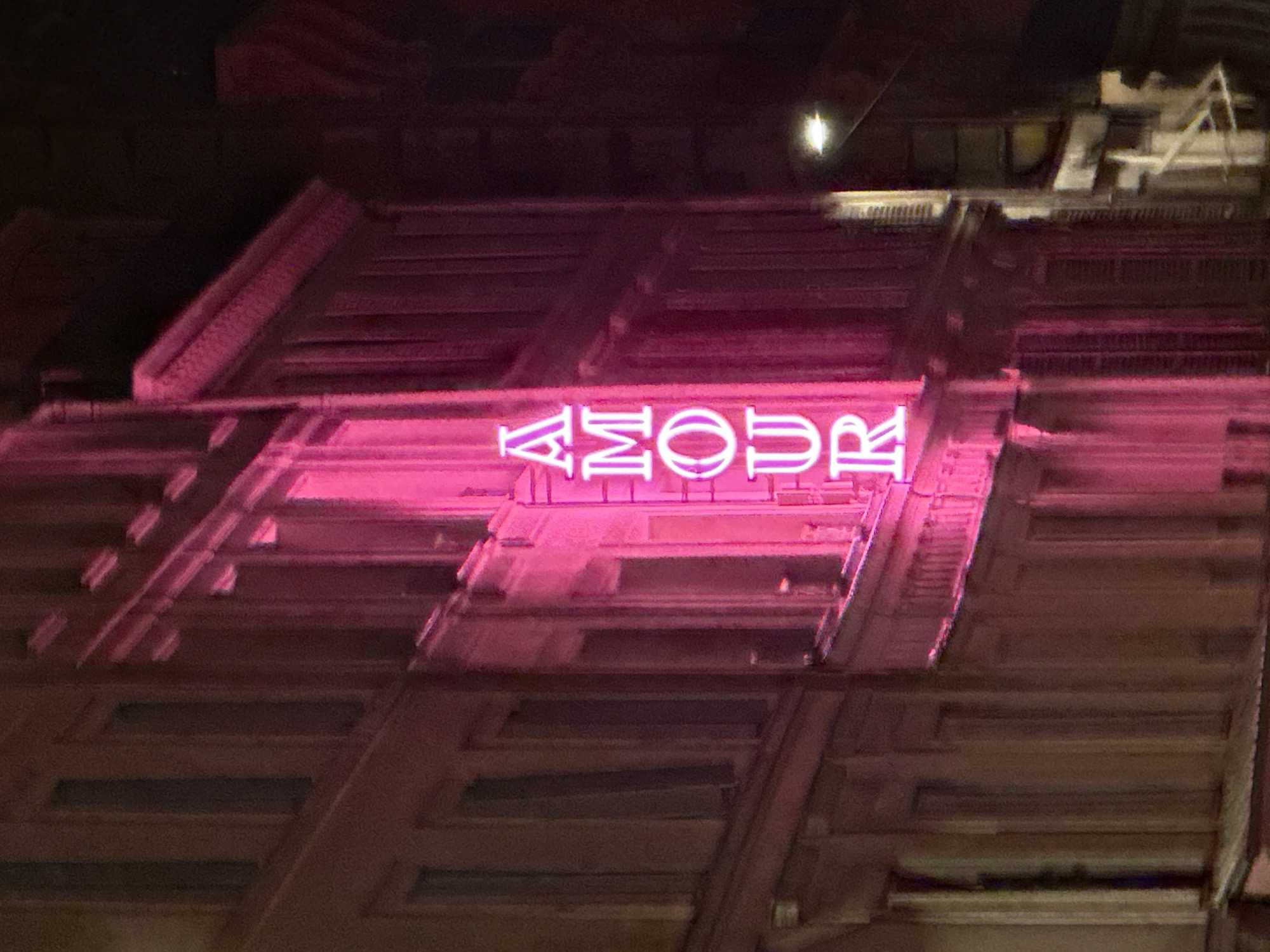 Evening stroll on wet Paris streets near neon-lit building