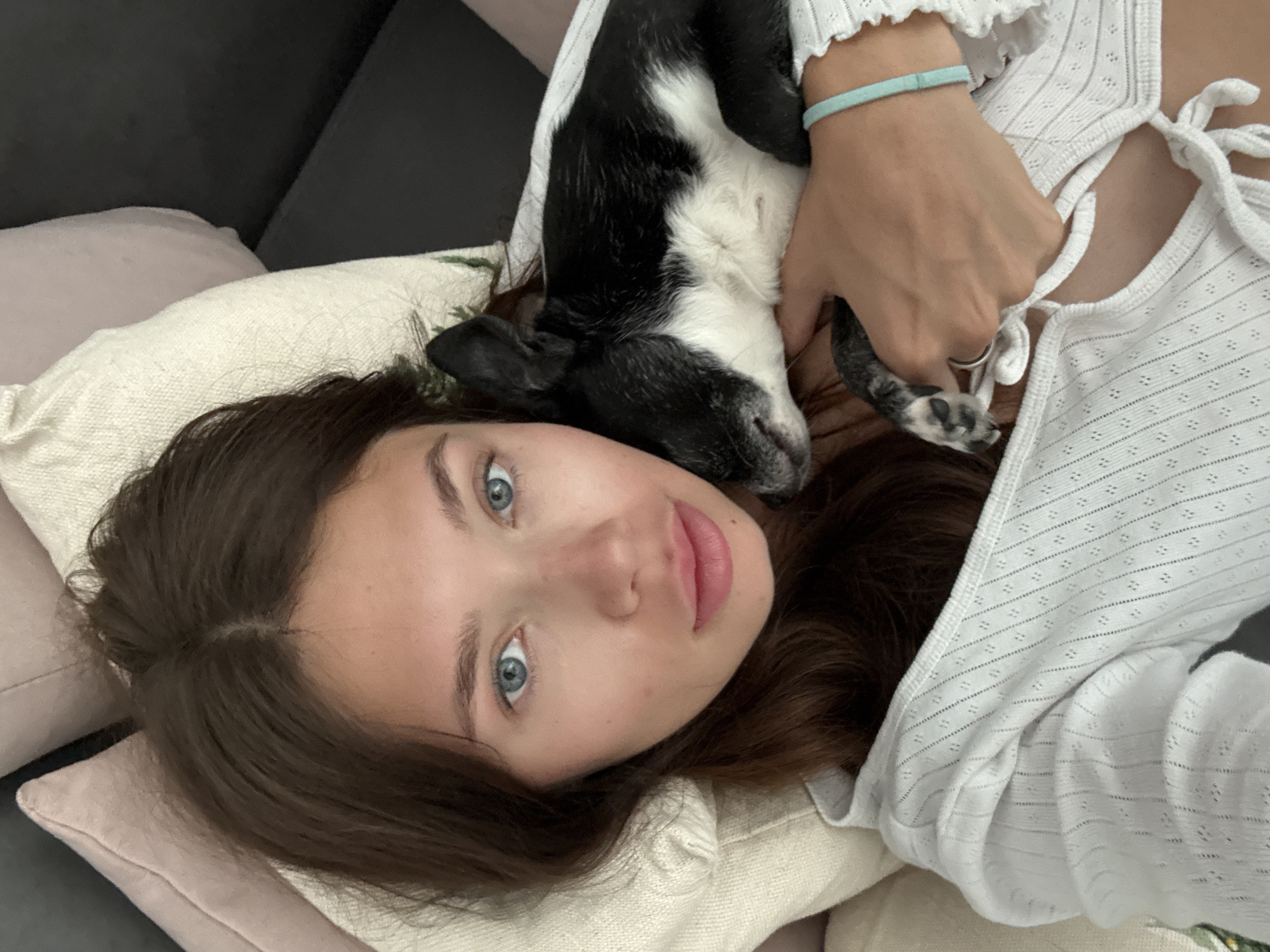 Woman relaxes with black and white dog on sofa