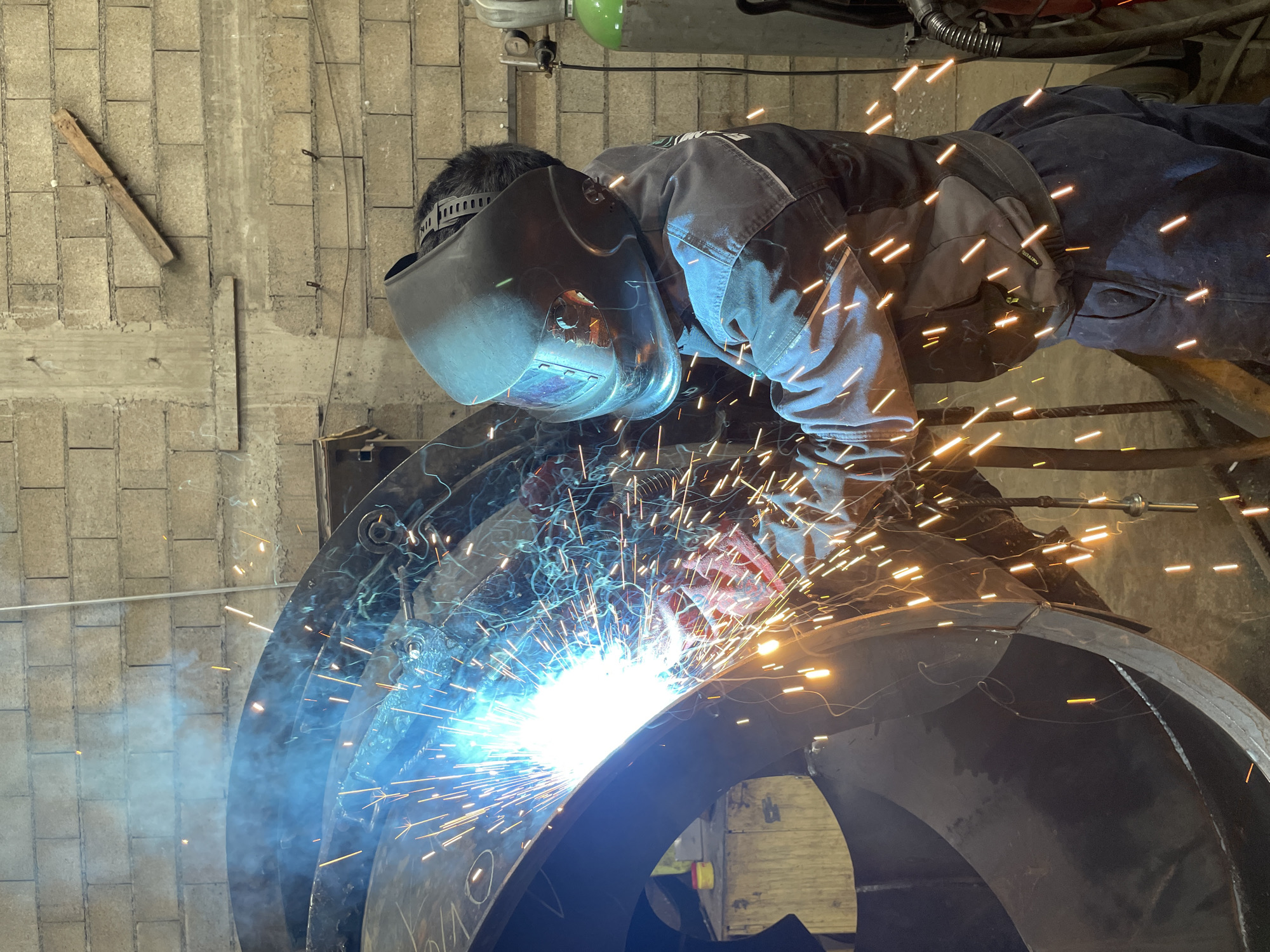Welder fabricates curved metal structure in Montenegro workshop