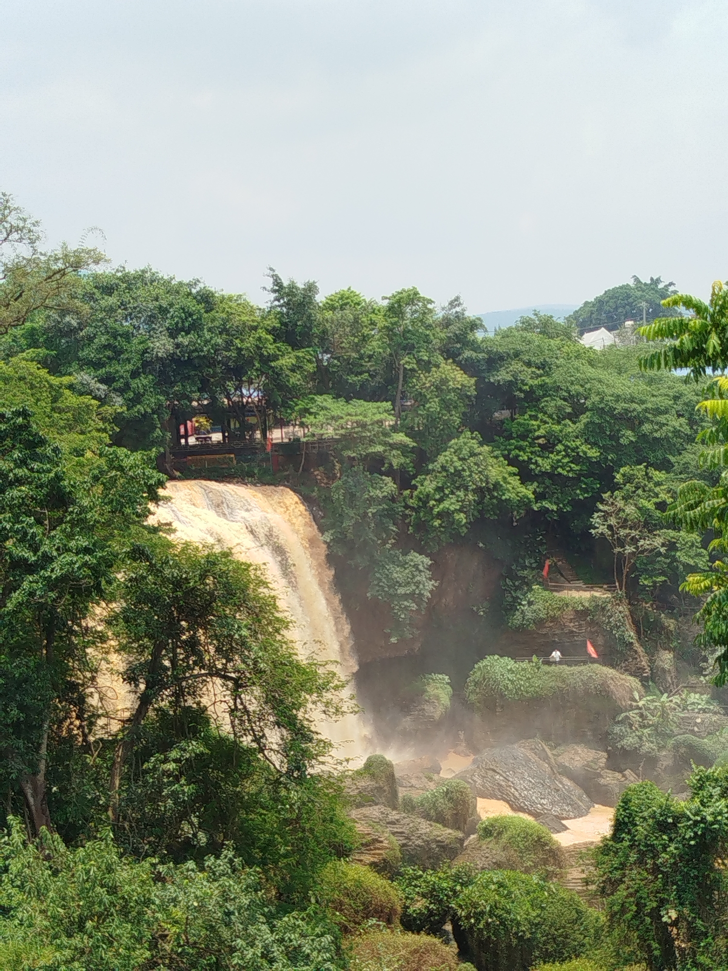 Tourist documents Vietnamese waterfalls and religious statues during morning visit