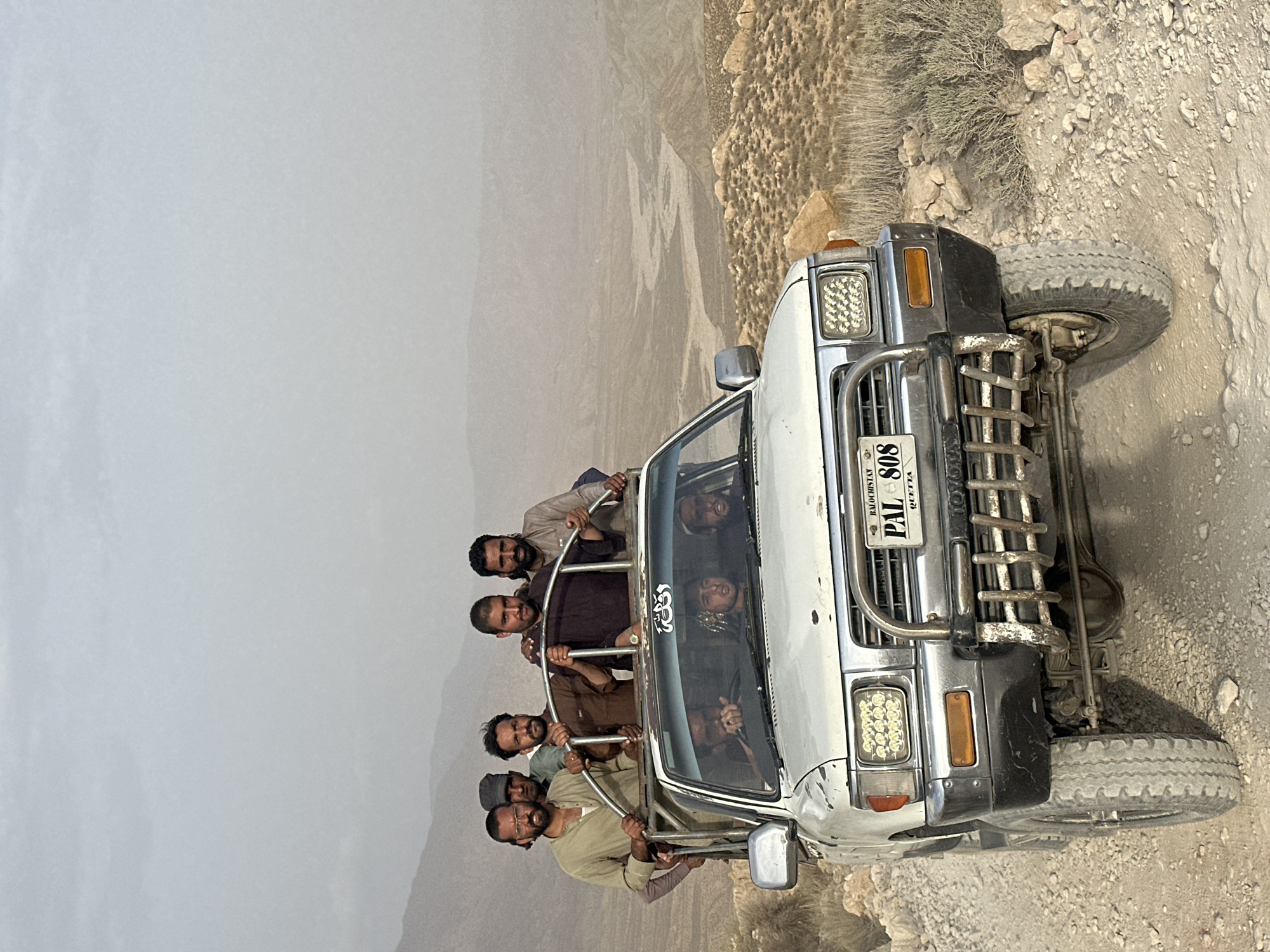 Group rides roll-cage Hilux through arid mountain terrain near Quetta