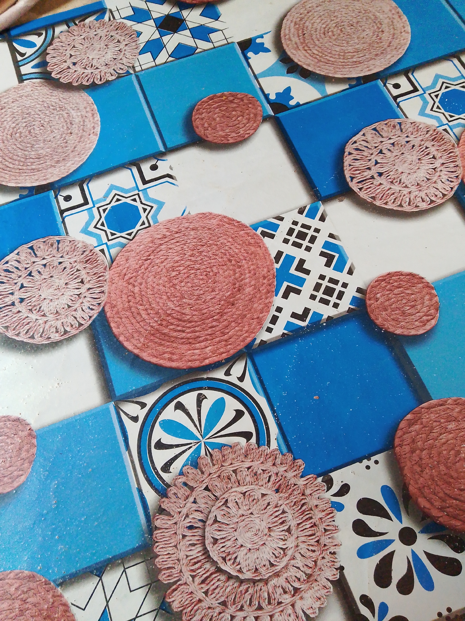 Pink crocheted coasters displayed on geometric tiles in Nigeria